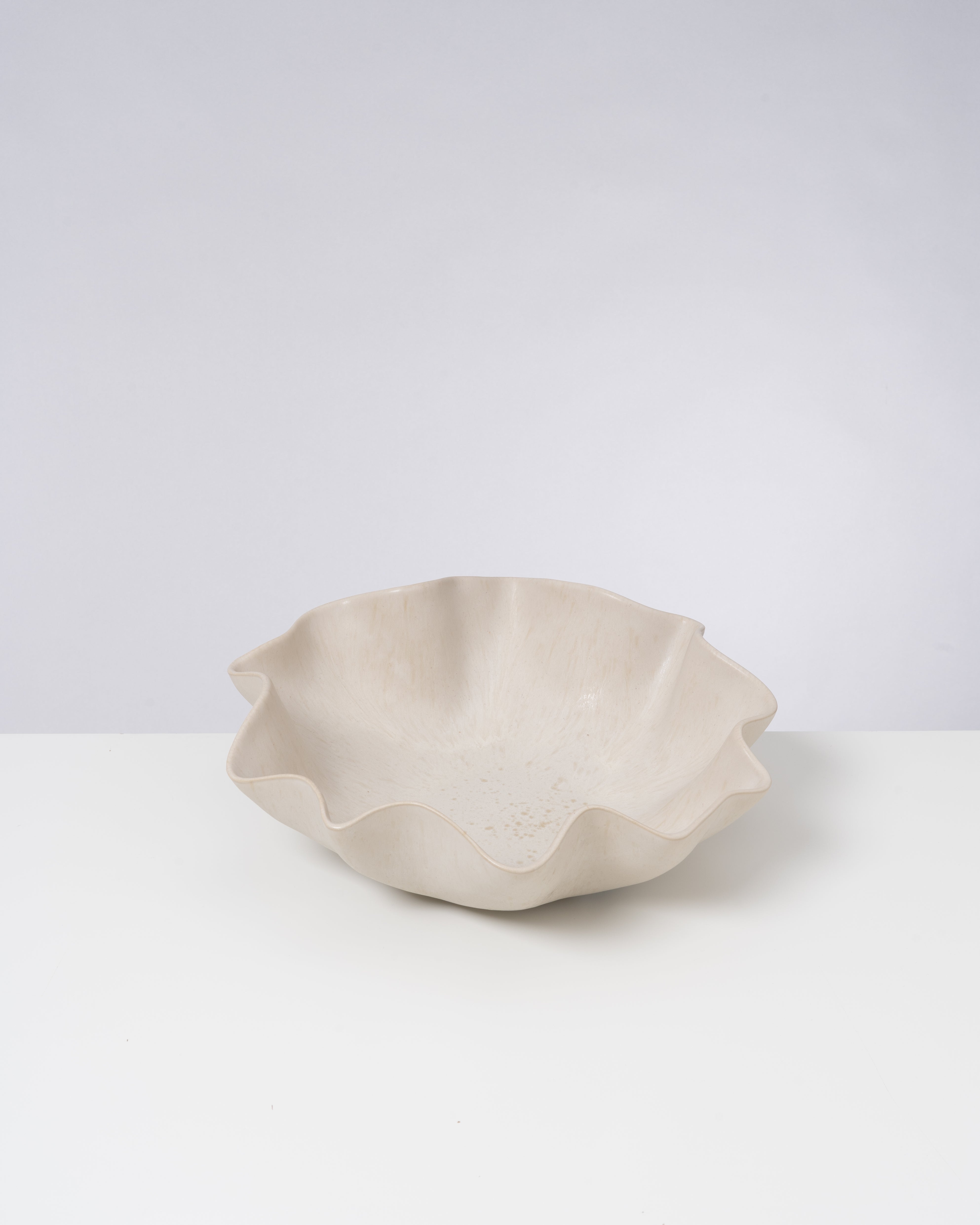 Beige Schale mit unregelmäßig geschwungenem Rand auf weißem Hintergrund.