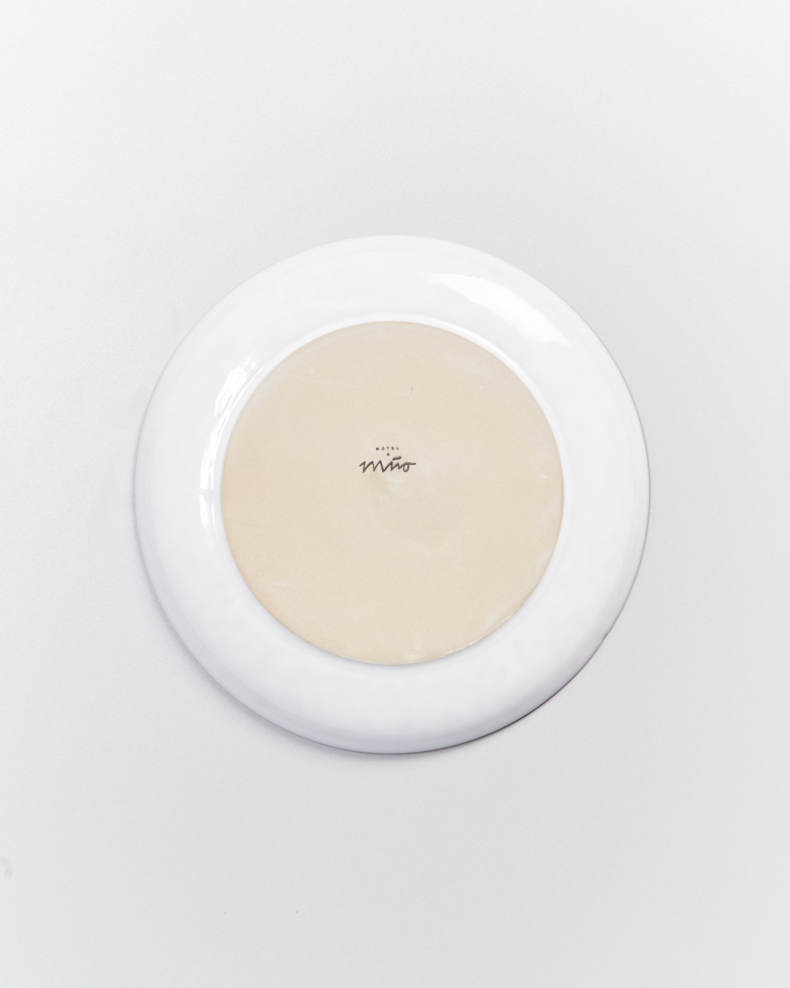 Unteransicht eines runden, weißen Tellers mit einem Markenzeichen in der Mitte des Bodens.