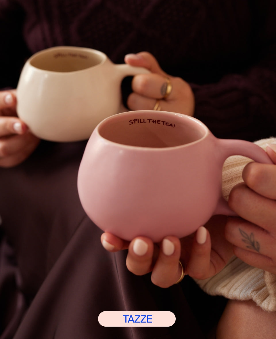 Zwei Personen halten je eine pastellfarbene Tasse mit der Aufschrift "SPILL THE TEA".