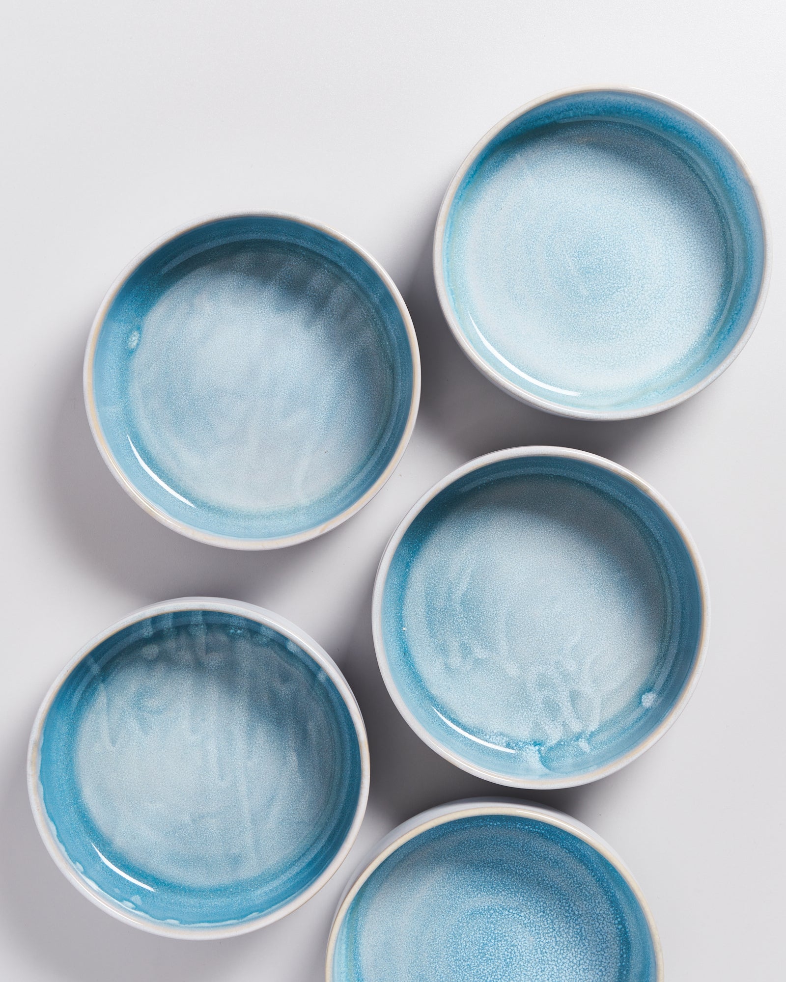 Sechs runde Teller mit blauem Farbverlauf auf weißem Hintergrund angeordnet.