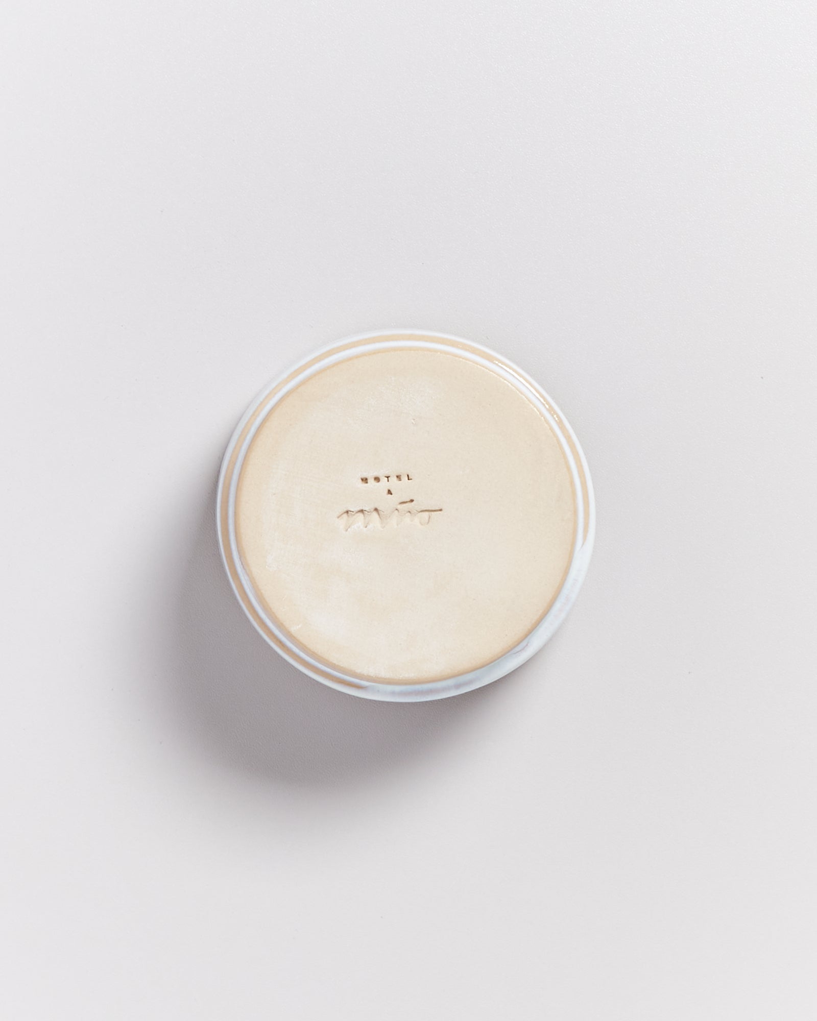 Runder Deckel auf einem weißen Hintergrund mit unleserlicher Prägung in der Mitte.