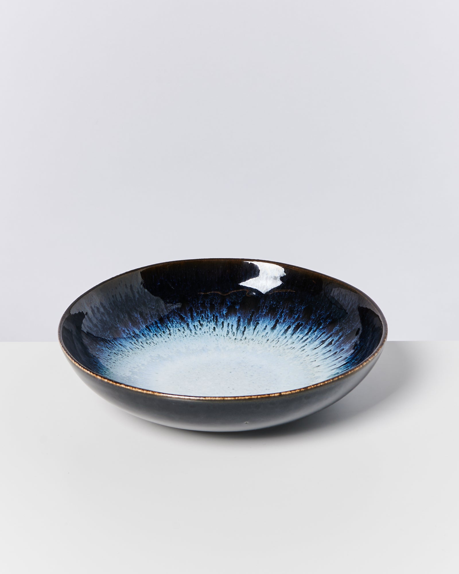 Eine flache, runde Schale mit blauem und schwarzem Farbverlauf auf weißem Hintergrund.