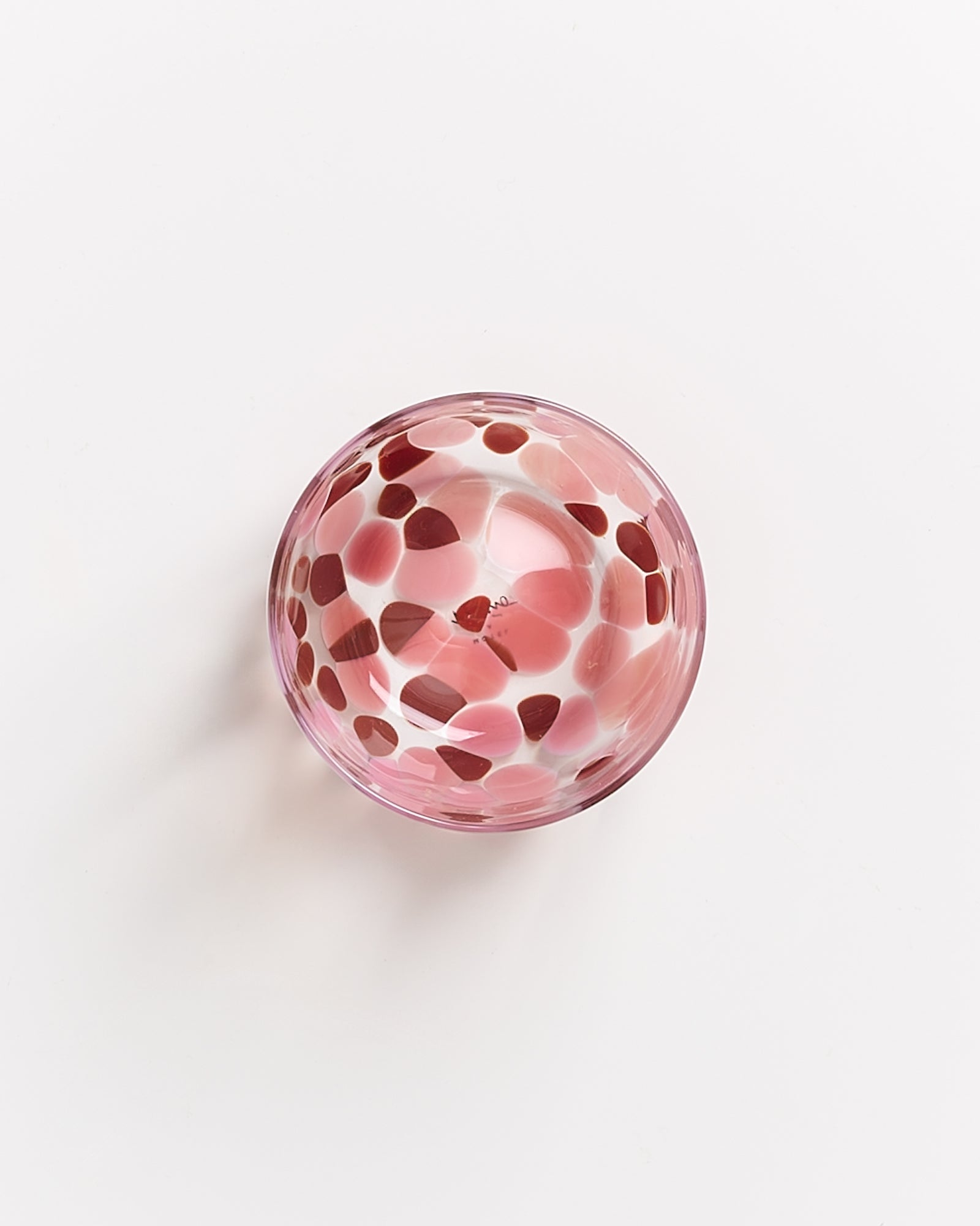 Rosa Glasschale mit roten und weißen Mustern auf weißem Hintergrund.