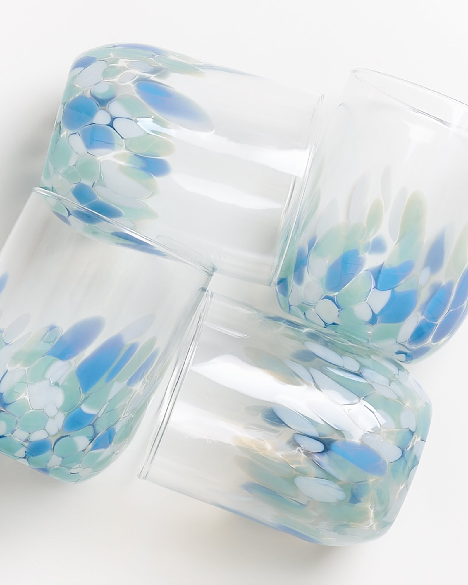 Vier Glasschalen mit abstraktem blau-grünem Muster, die übereinander gestapelt sind.