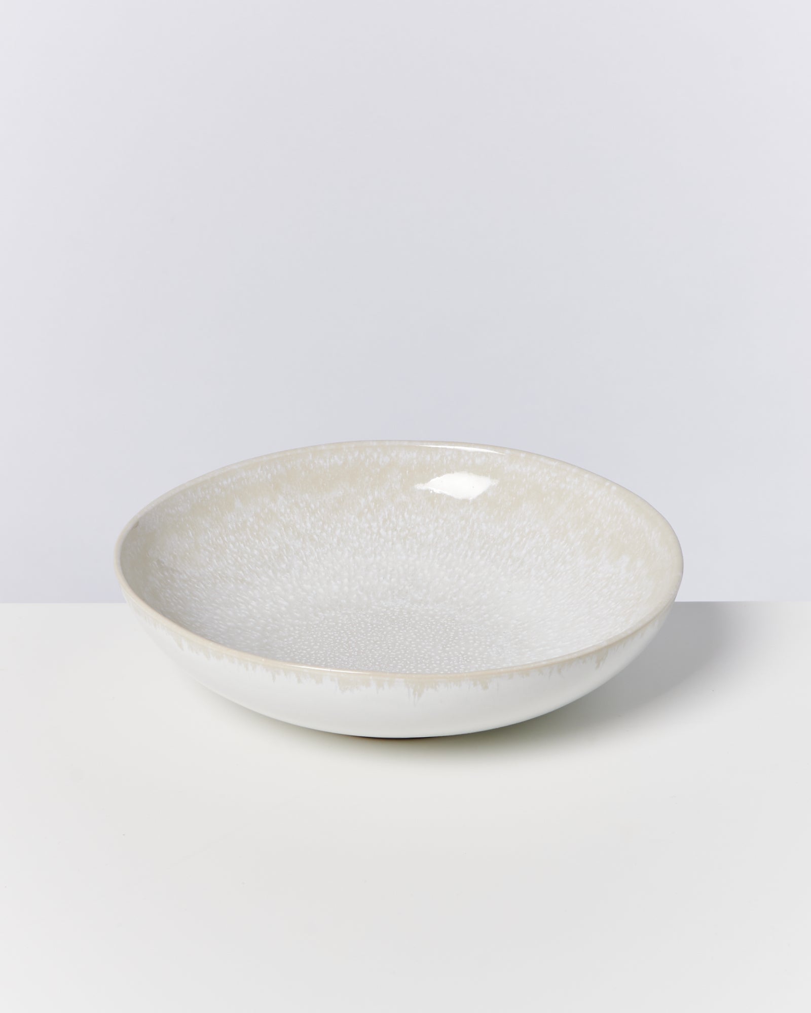 Beiger Keramikteller mit leichter Musterung auf weißem Hintergrund.