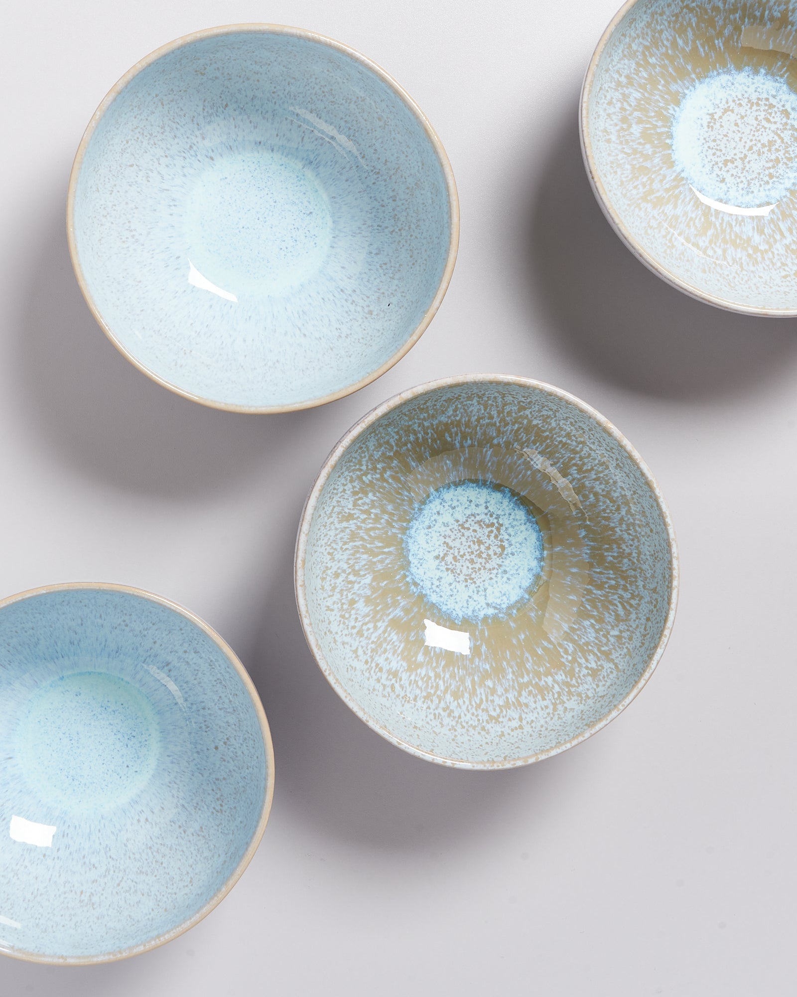 Vier blau-weiße Keramikschalen mit gesprenkeltem Muster auf hellem Hintergrund.
