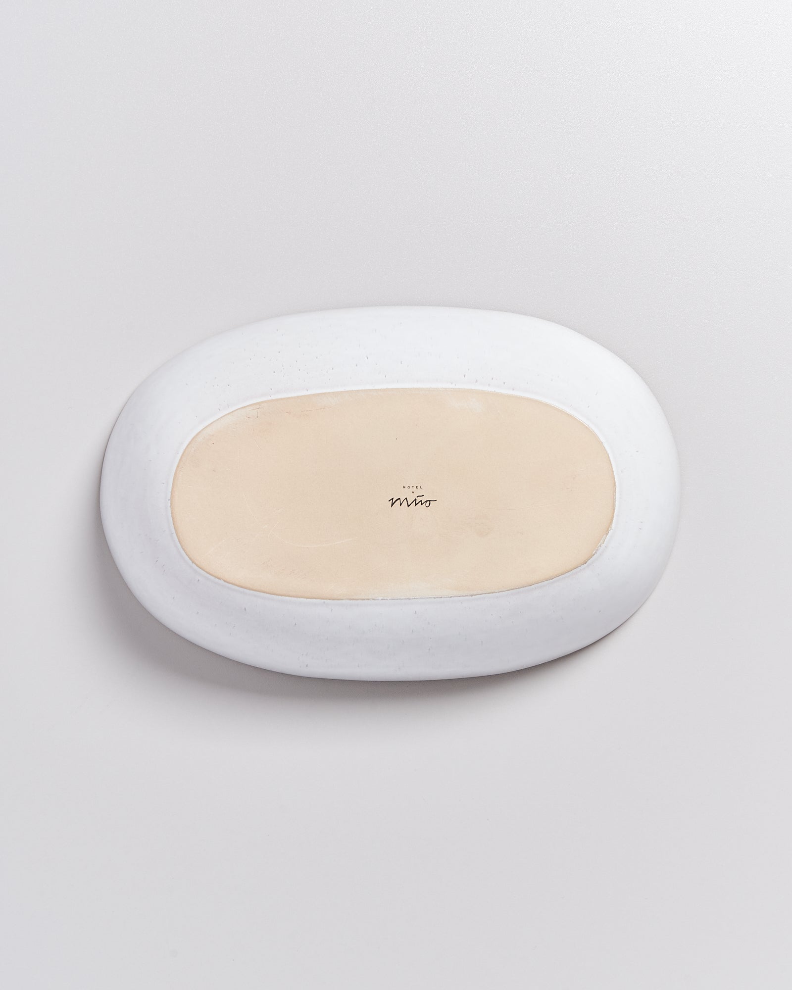 Weiße, ovale Seifenschale mit beige Innenseite auf weißem Hintergrund, beschriftet mit "Hotel Mirò".