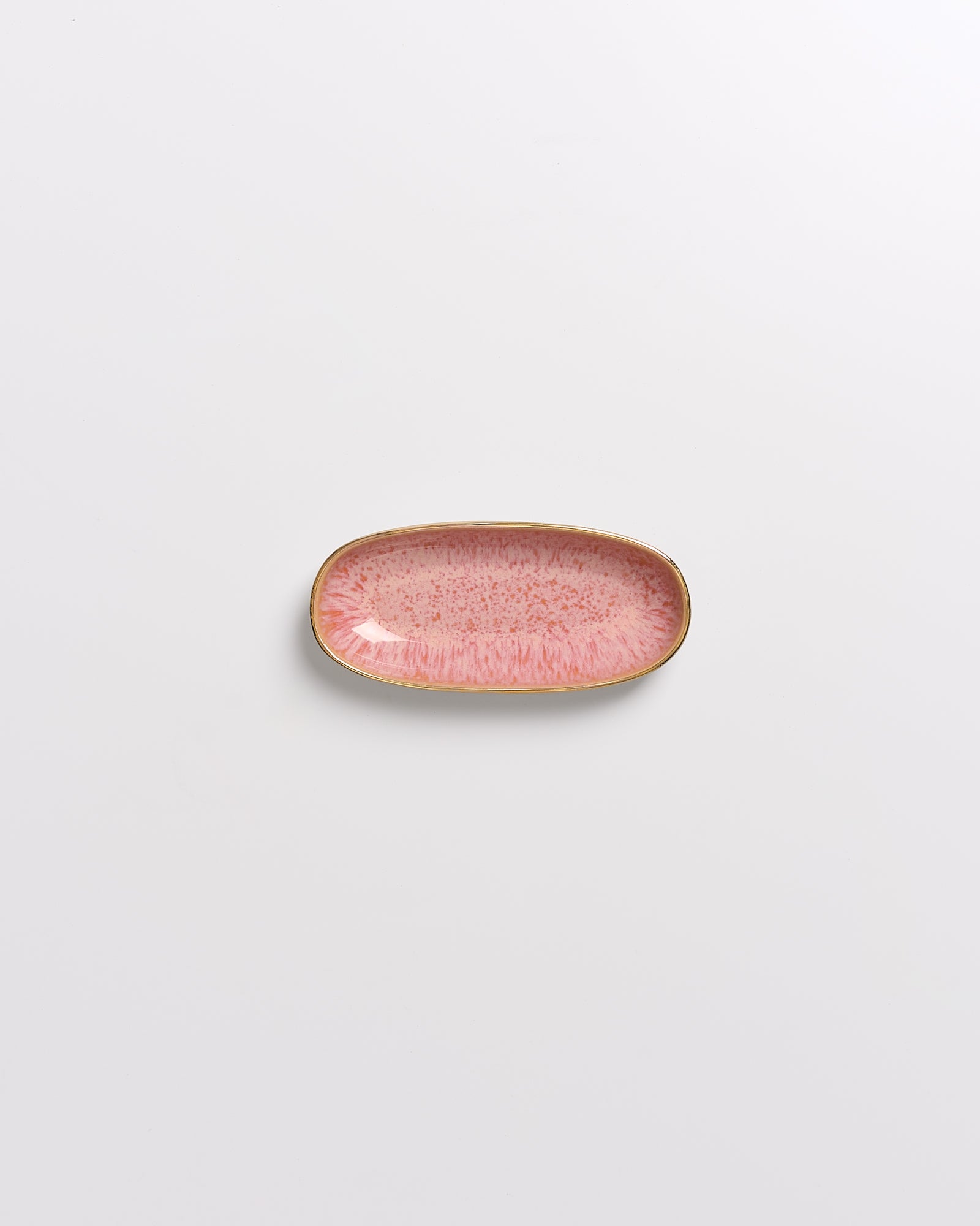 Kleiner, rosafarbener, rechteckiger Teller mit goldenem Rand auf weißem Hintergrund.
