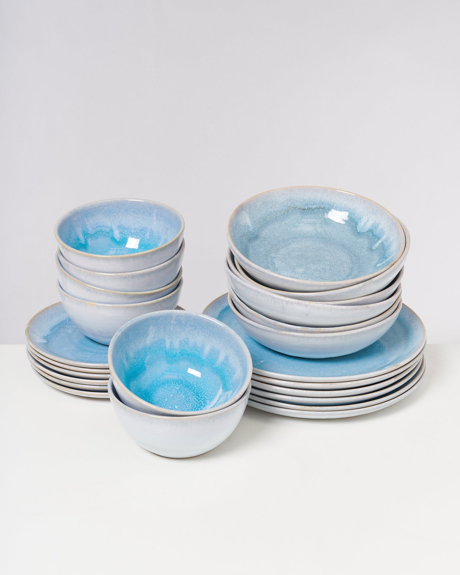 Gestapelte blaue Schalen und Teller auf einem weißen Tisch.