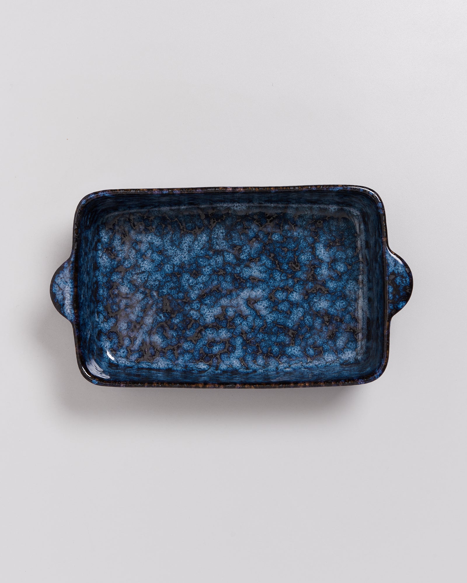 Rechteckige, blau-schwarz marmorierte Keramik-Auflaufform mit zwei Henkeln auf weißem Hintergrund.
