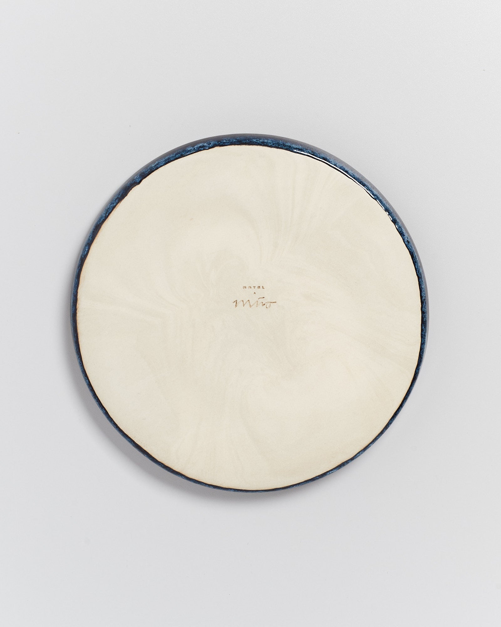 Runde Keramikscheibe mit heller Oberfläche und dunklem Rand, zeigt eine Inschrift in der Mitte auf weißem Hintergrund.