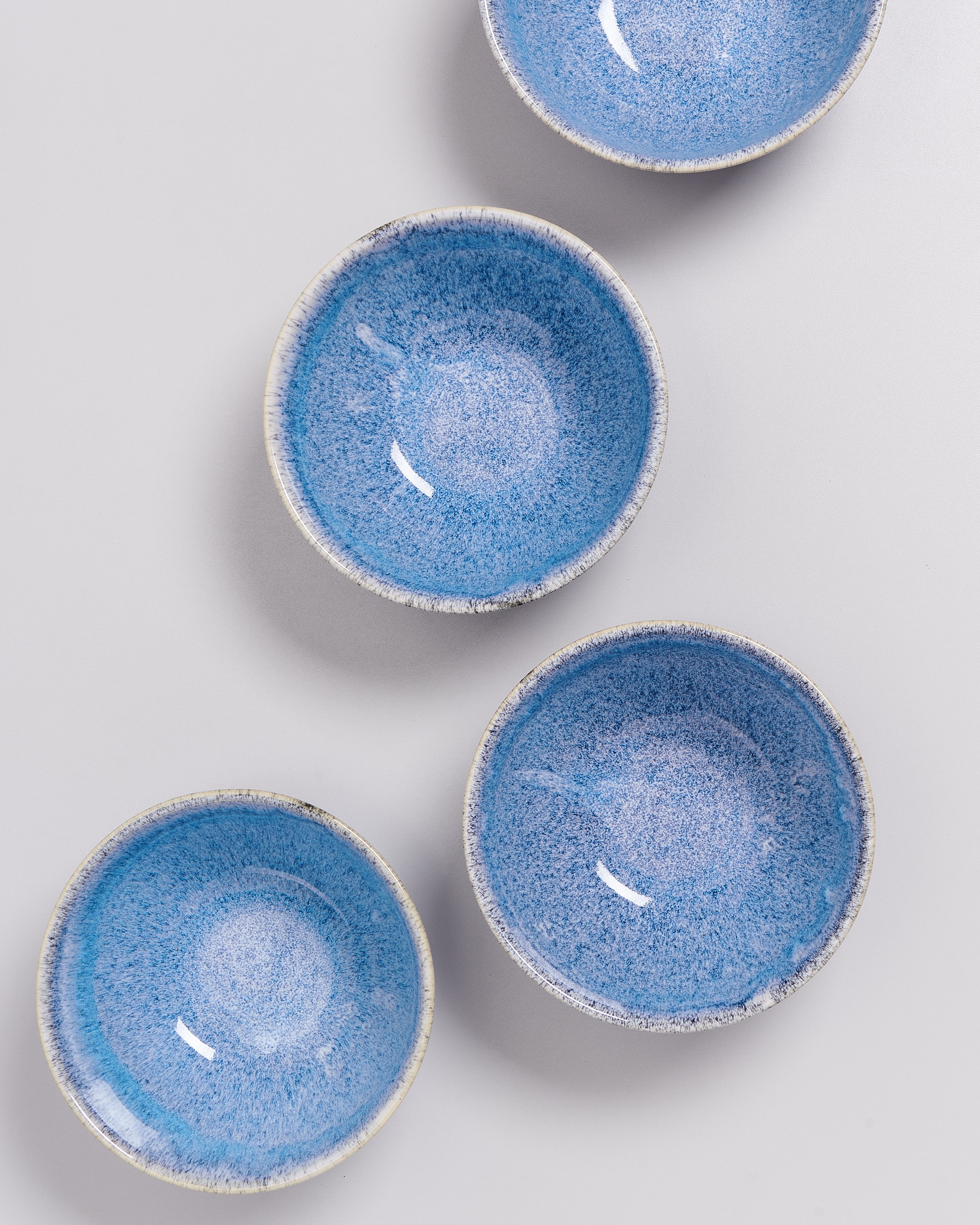 Vier blaue Keramikschalen mit gesprenkeltem Muster auf einem weißen Hintergrund.