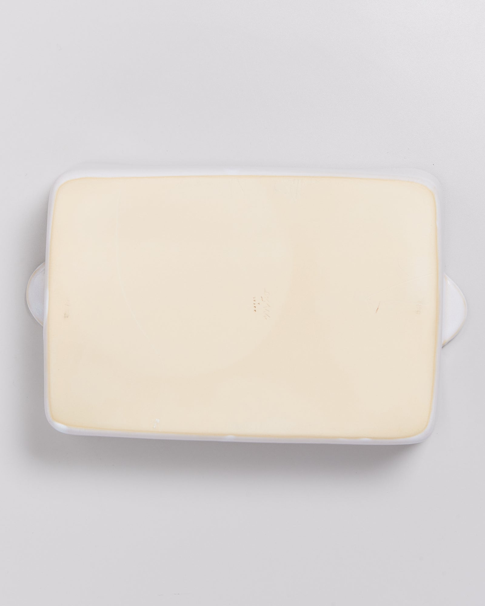 Weiße rechteckige Keramikauflaufform mit Griffen auf beiden Seiten, auf hellgrauem Hintergrund.