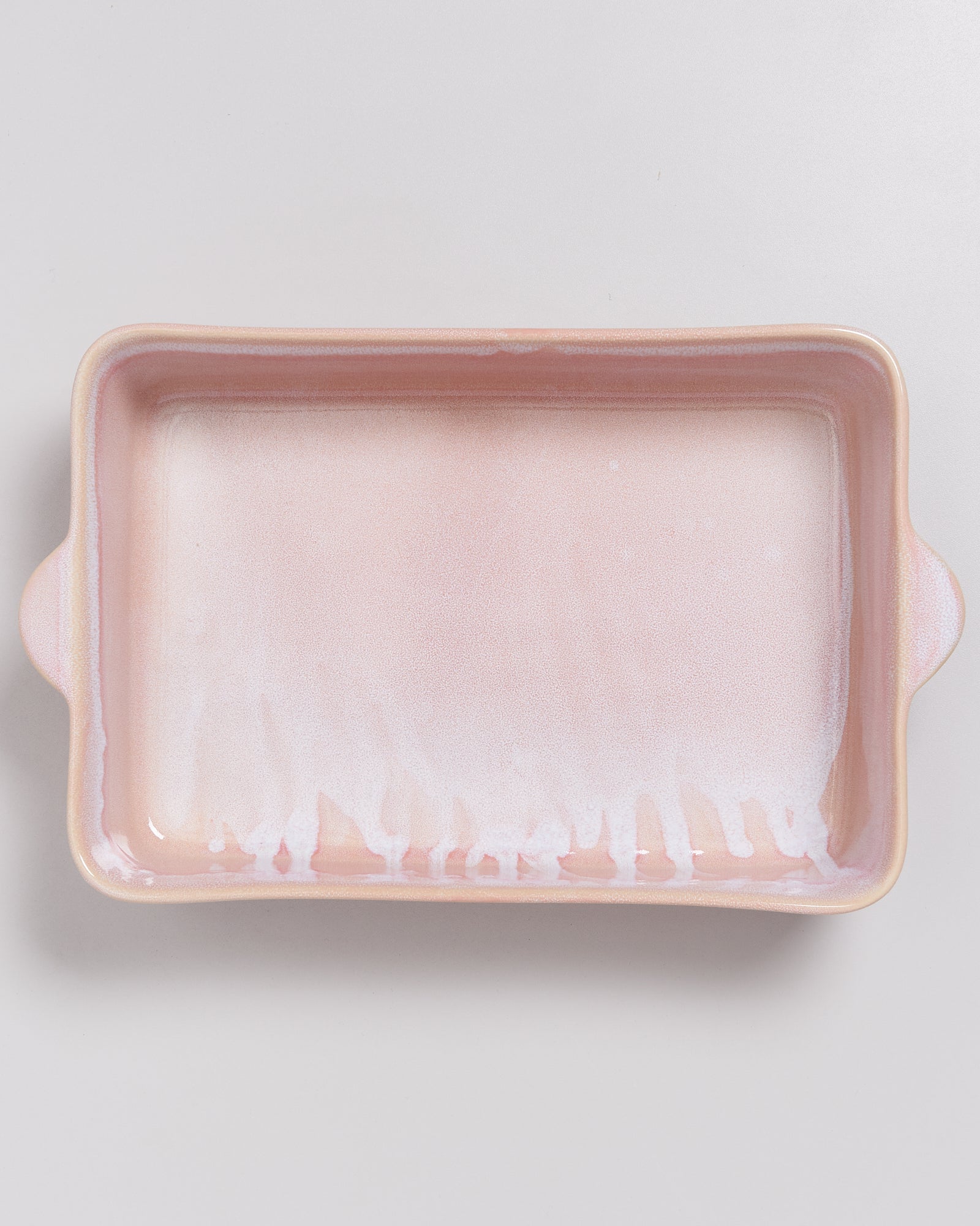 Rechteckige rosafarbene Keramikauflaufform mit weißem Muster auf einem hellen Hintergrund.