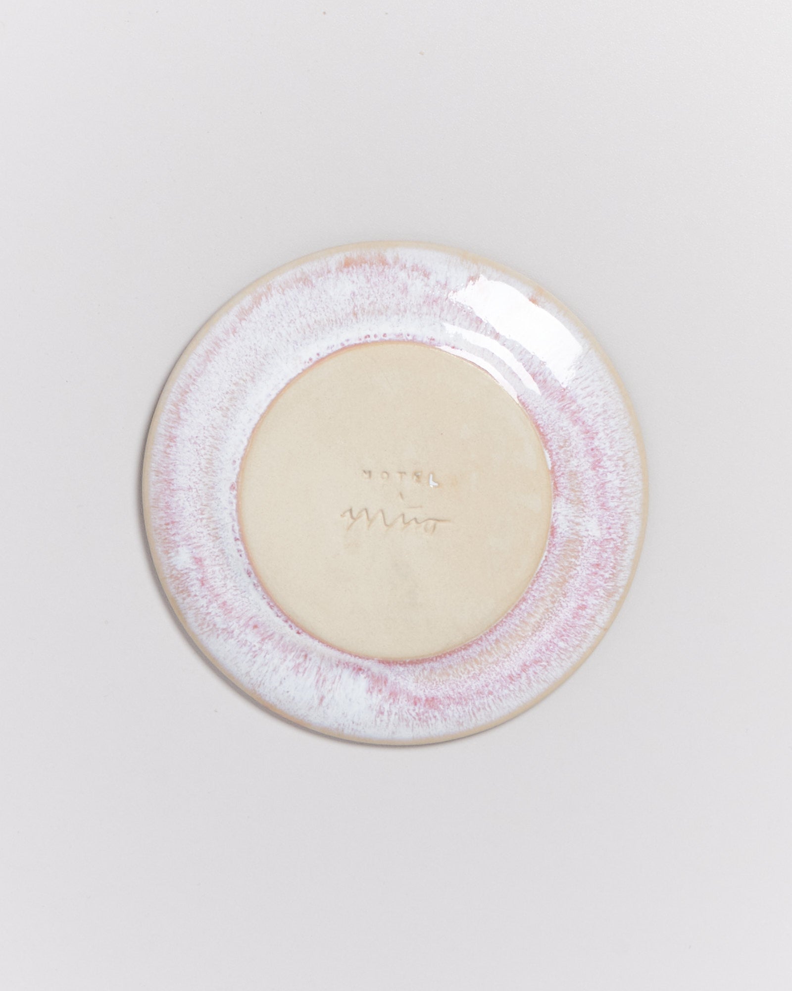 Runder Teller mit rosa und cremefarbenem Rand, zeigt eine Bodenmarke mit der Aufschrift „Hotel“.