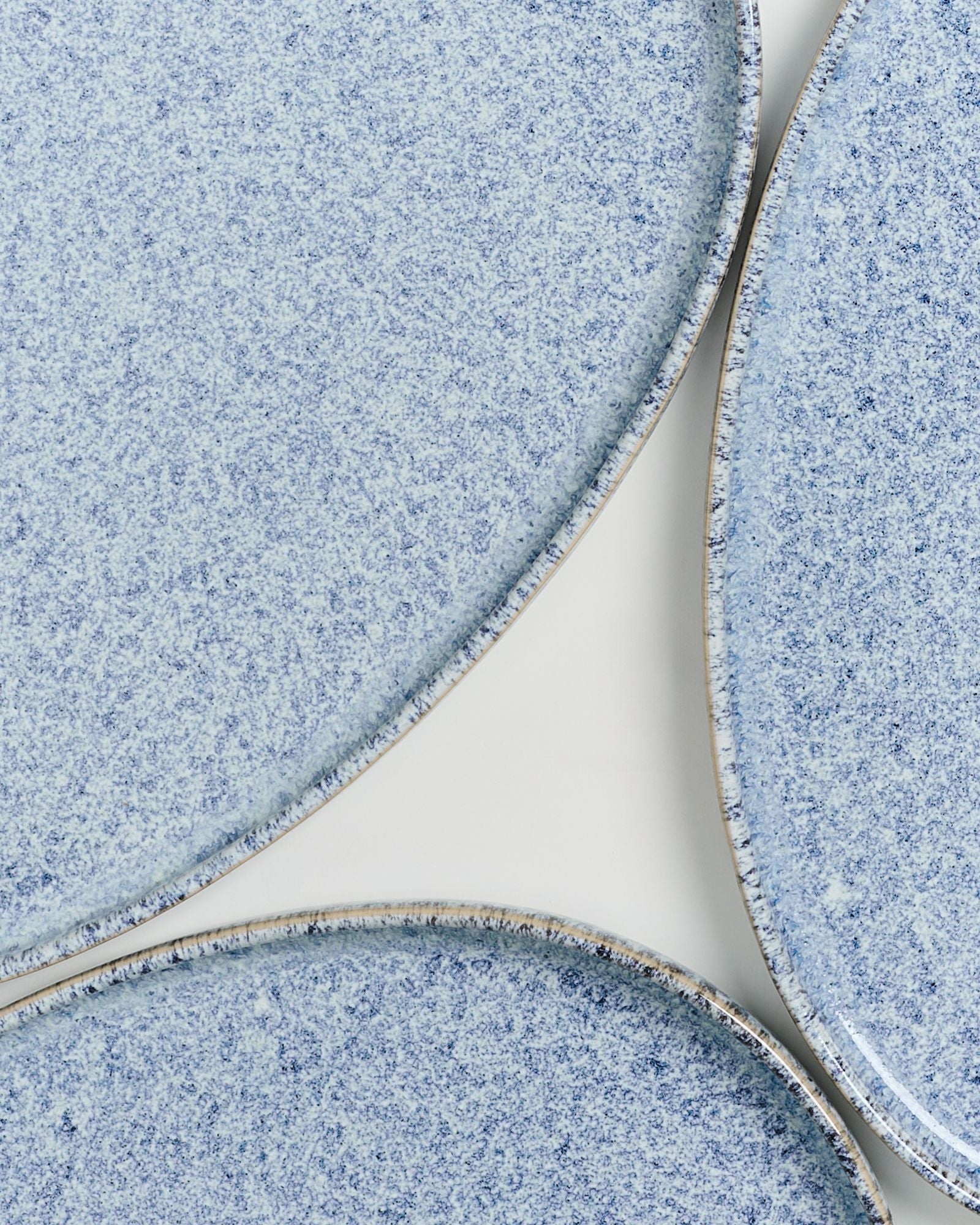 Nahaufnahme von drei blaugemusterten Tellern mit gesprenkelter Oberfläche auf einem weißen Hintergrund.