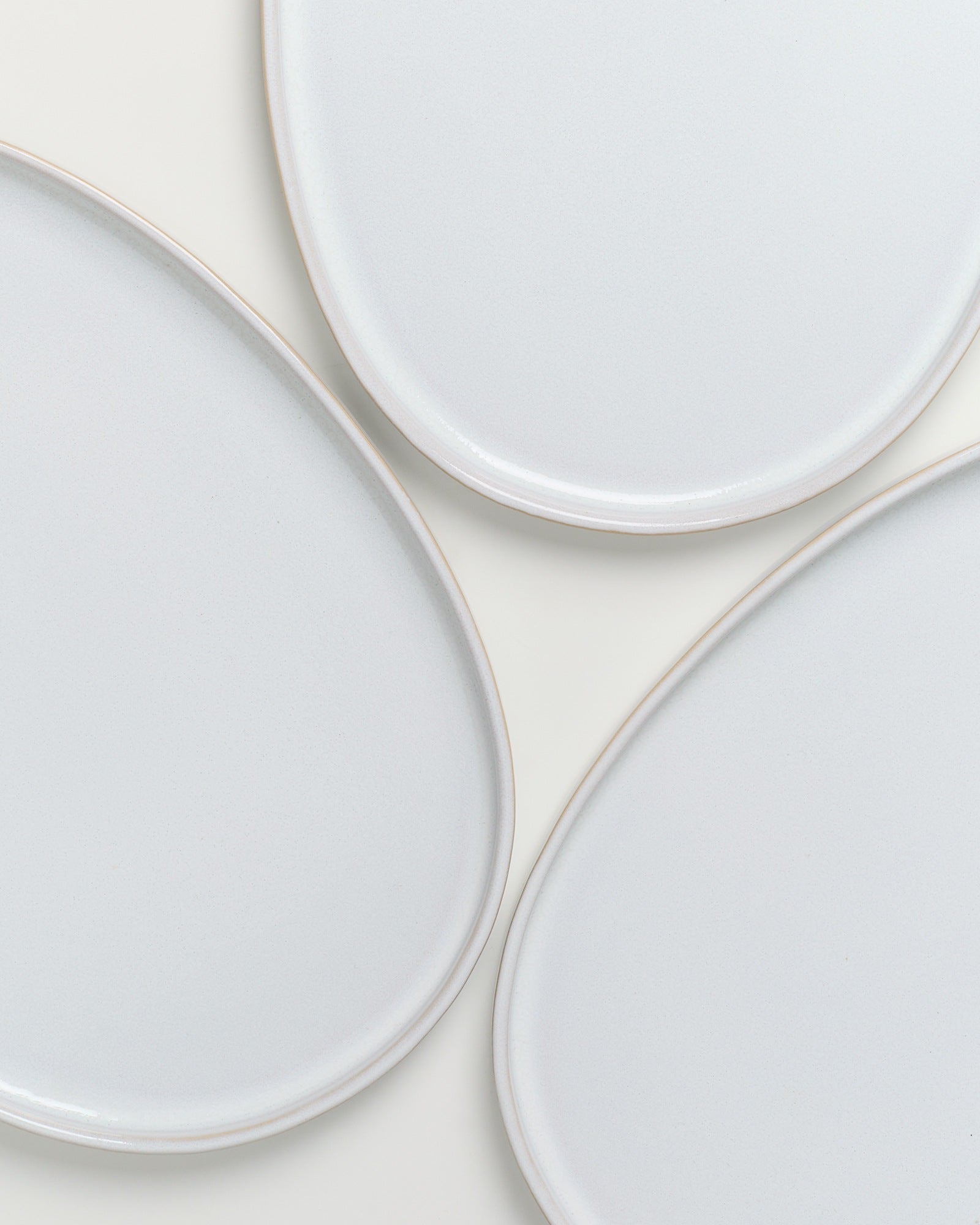 Drei weiße, ovale Teller mit leicht erhabenen Rändern auf weißem Hintergrund.