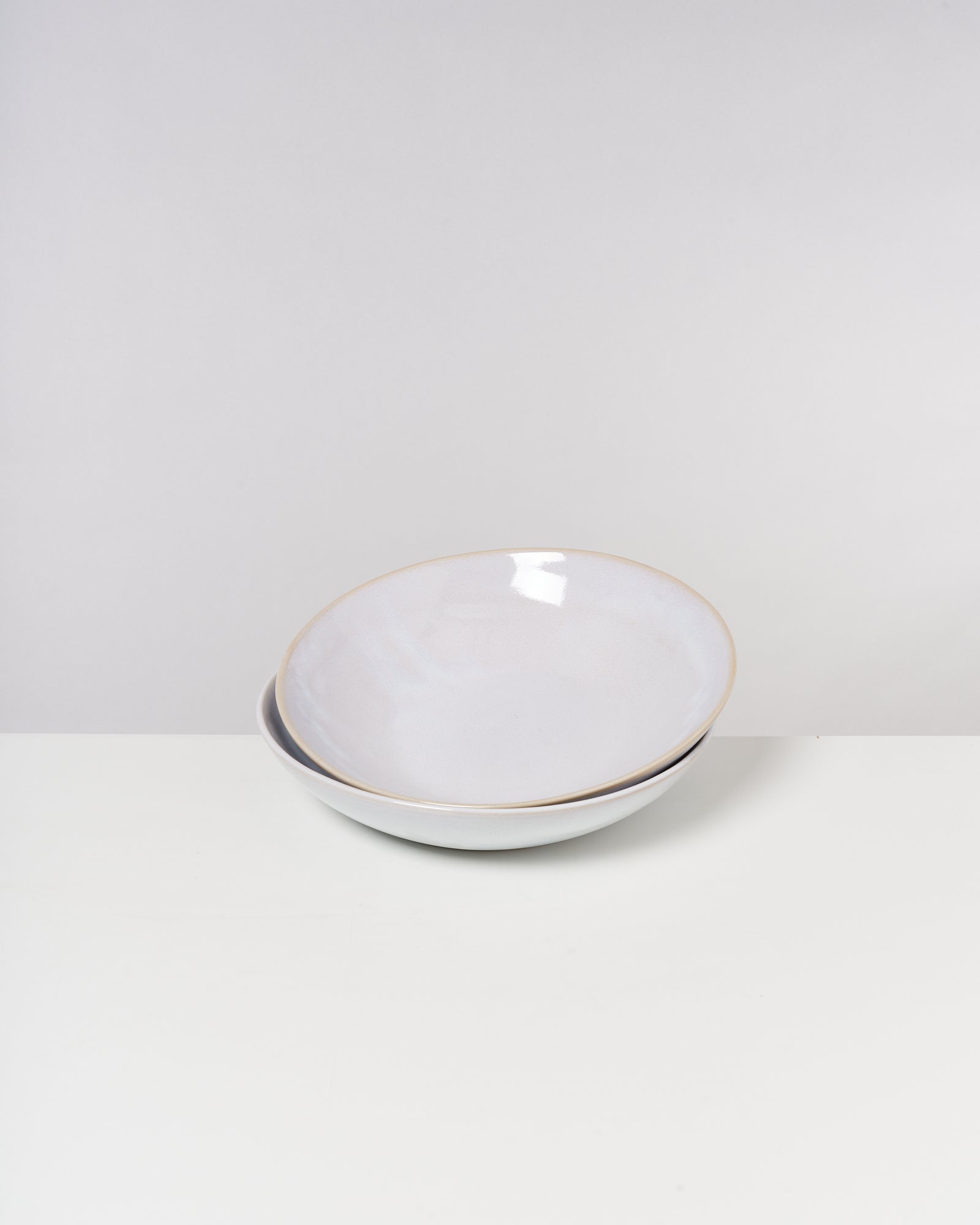 Zwei weiße, leicht ineinander gestapelte Schüsseln auf weißem Hintergrund.