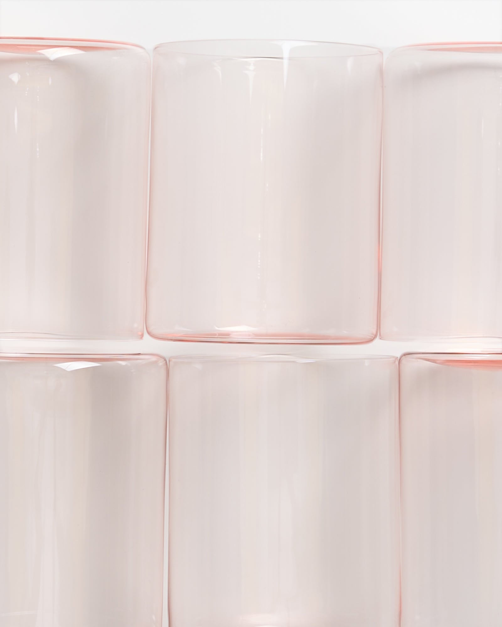 Sechs durchsichtige, leicht rosa Gläser sind in zwei Reihen zu je drei gestapelt.