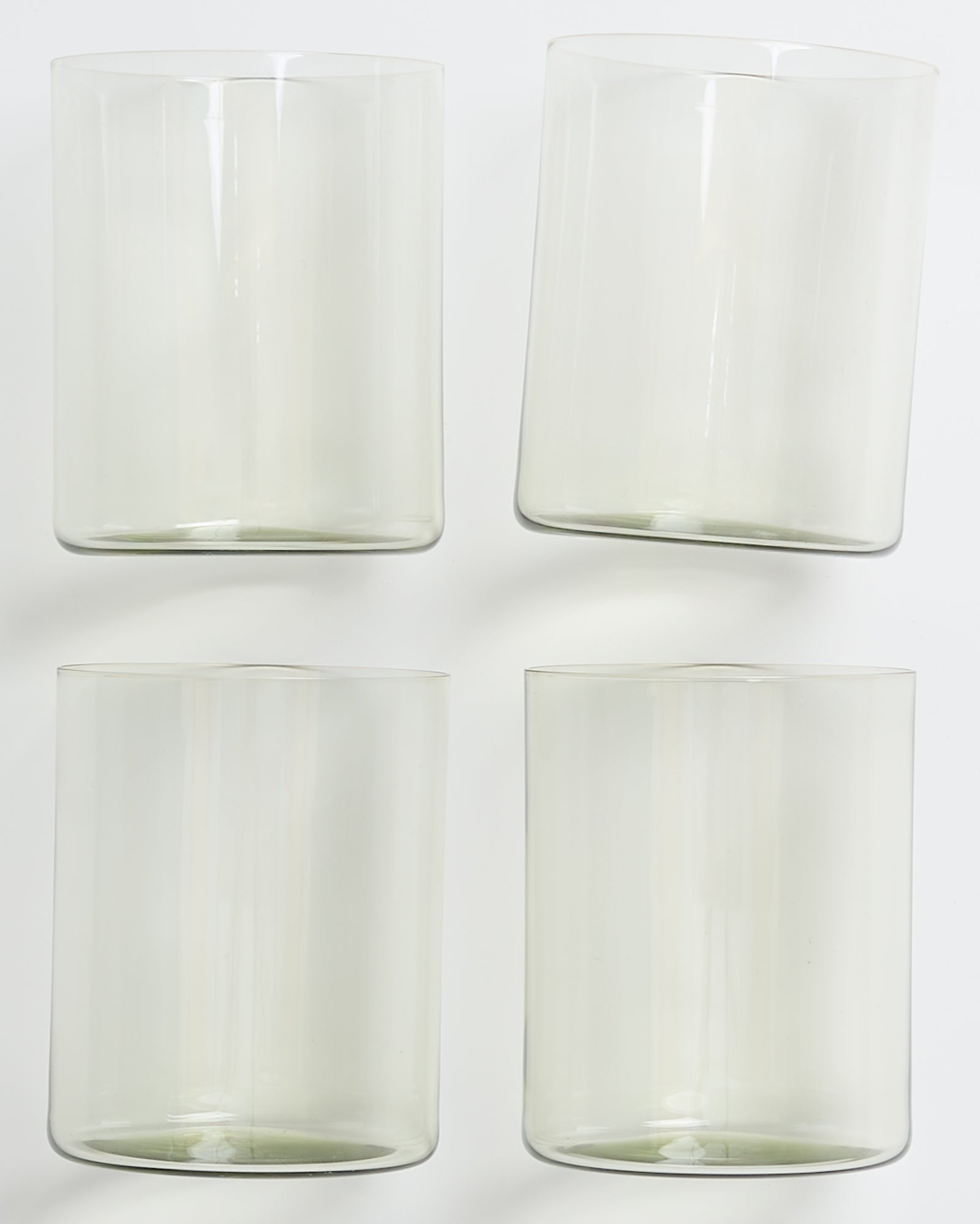 Vier transparente Gläser mit leicht grünlichem Schimmer auf weißem Hintergrund.