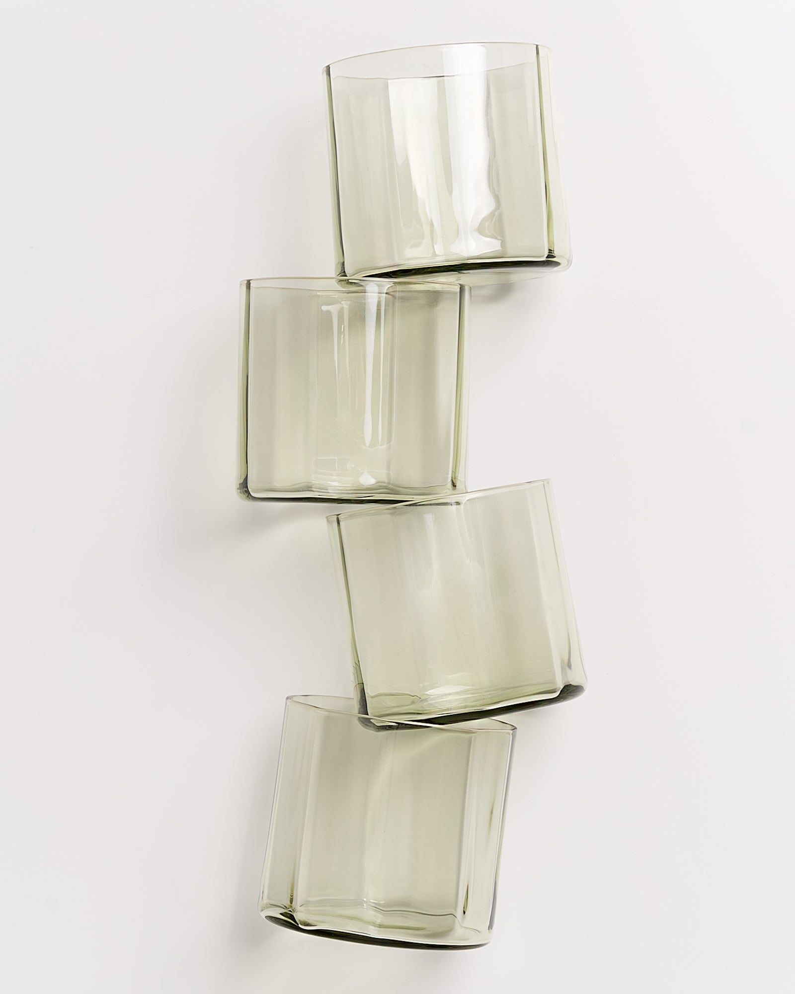 Vier übereinander gestapelte, leicht getönte Glasbecher auf weißem Hintergrund.