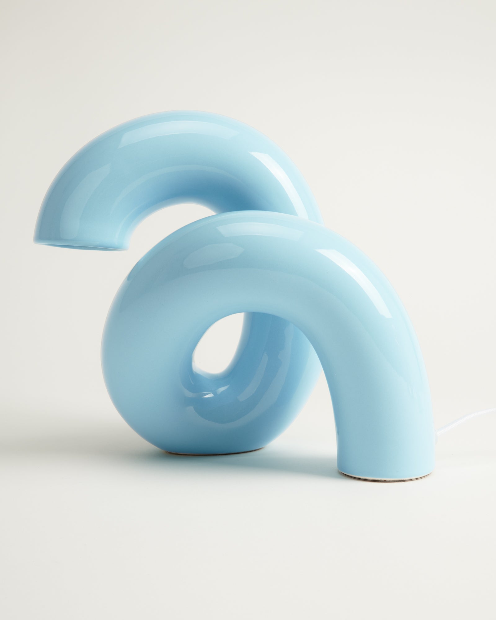 Blaue, geschwungene Tischlampe mit organischer Form auf weißem Hintergrund.