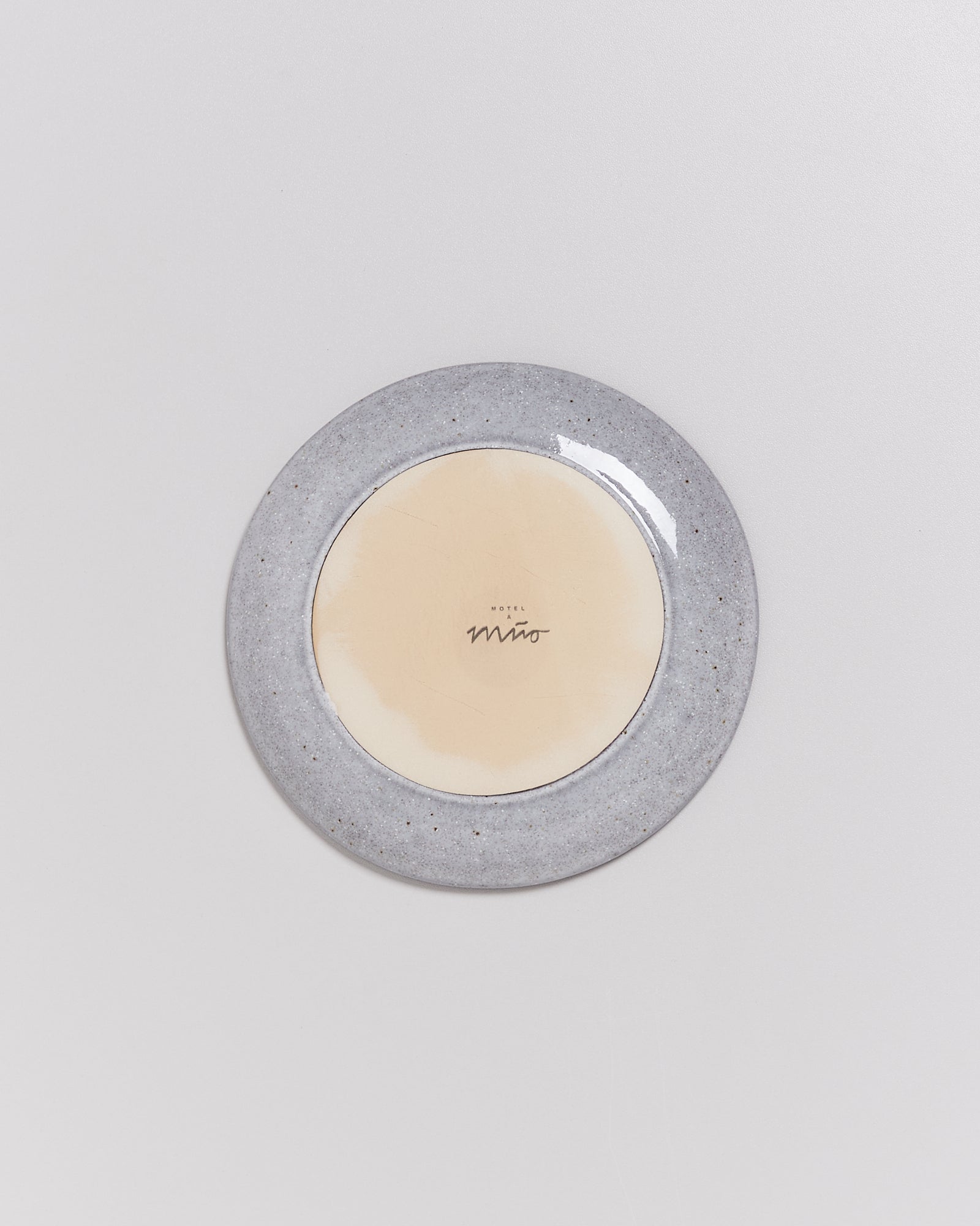 Grauer Keramikteller mit cremefarbener Mitte und dem Schriftzug "Hotel Miro" in der Mitte.