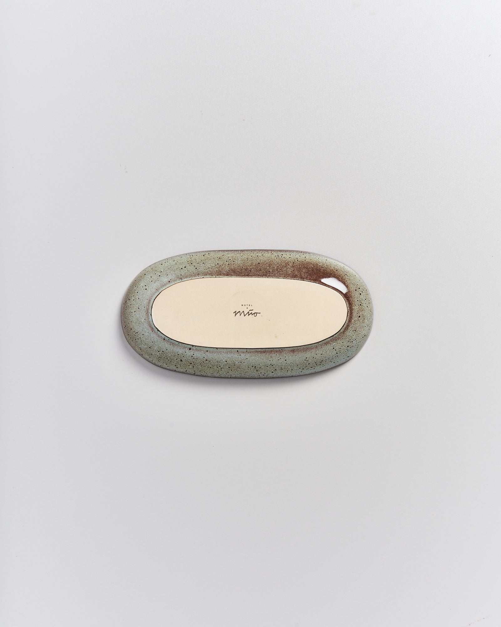 Rückseite eines ovalen Spiegels mit einem unregelmäßigen Rahmen und einem zentralen Etikett auf weißem Hintergrund.