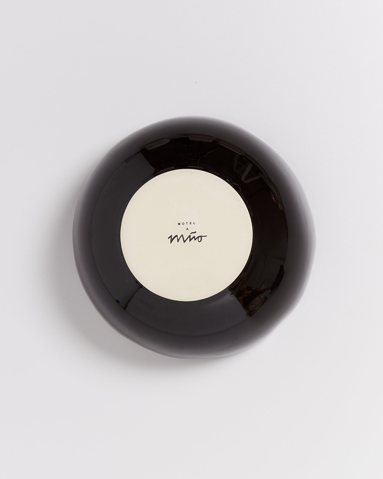 Schwarzer, runder Teller mit weißem Zentrum und dem Text "Motel a Miio" darauf.