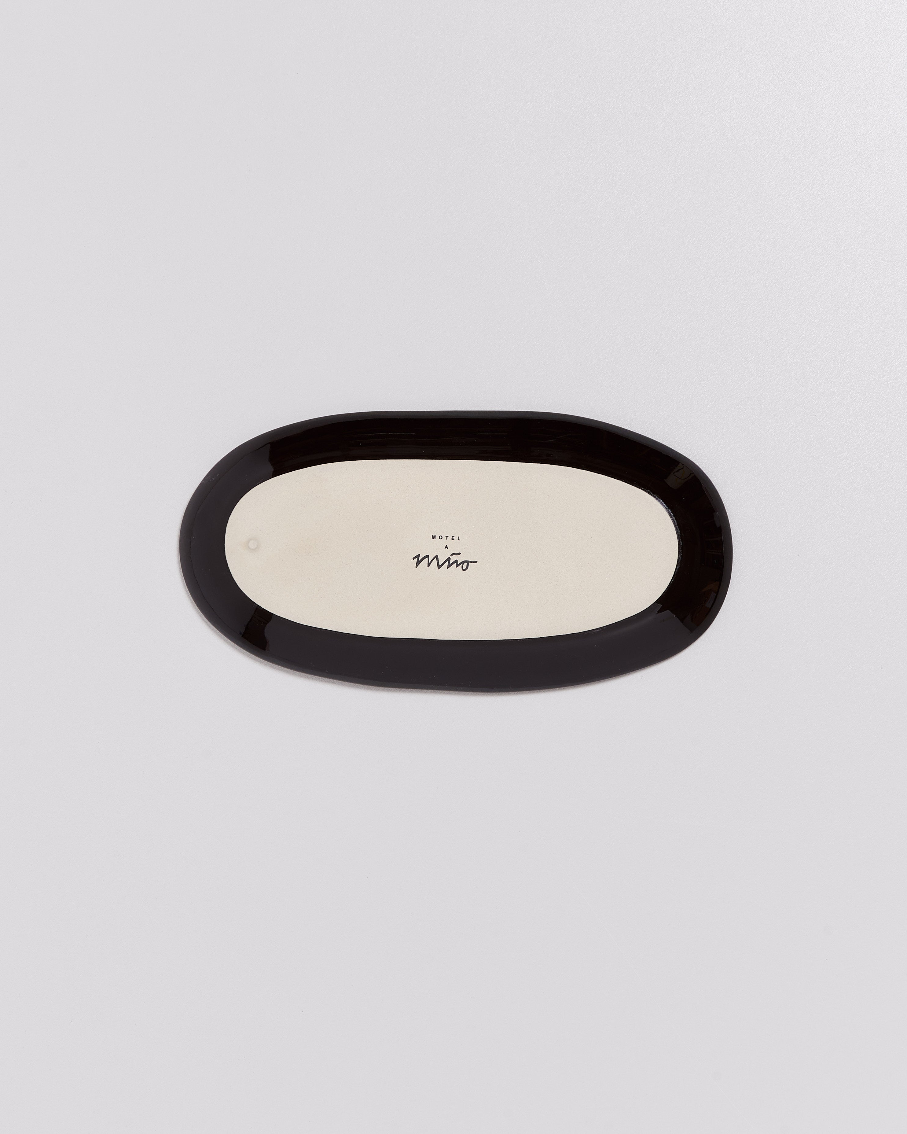 Ovaler Teller mit schwarzem Rand auf grauem Hintergrund, markiert mit "Hotel" und einer Unterschrift in der Mitte.