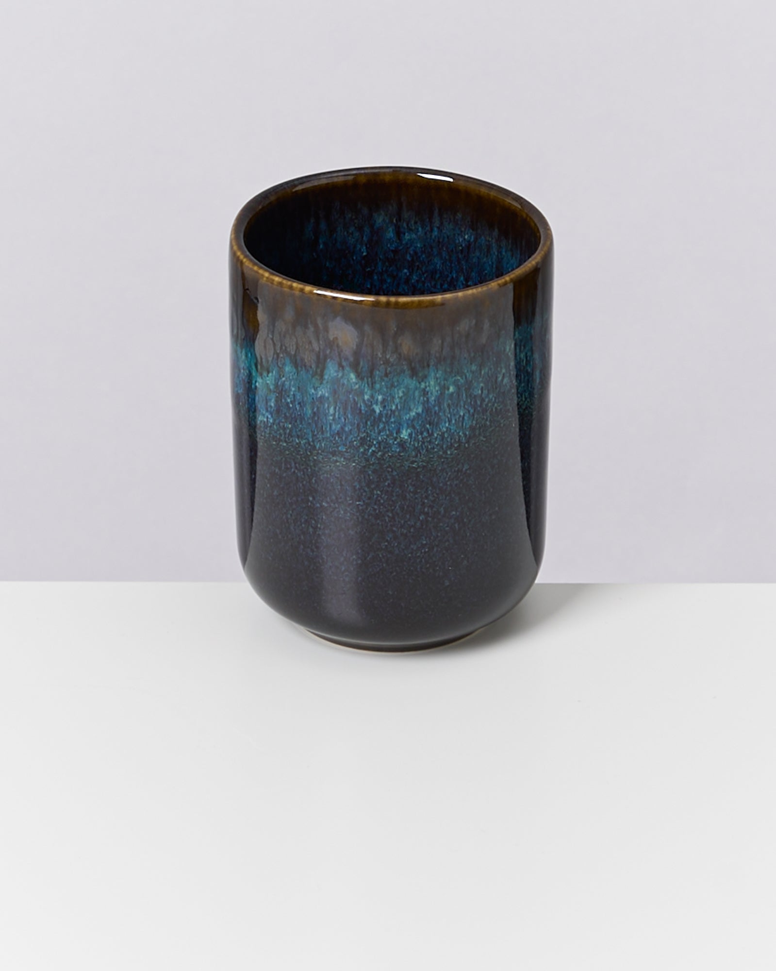 Keramiktasse in dunklem Blau mit verlaufendem Farbmuster auf weißem Hintergrund.