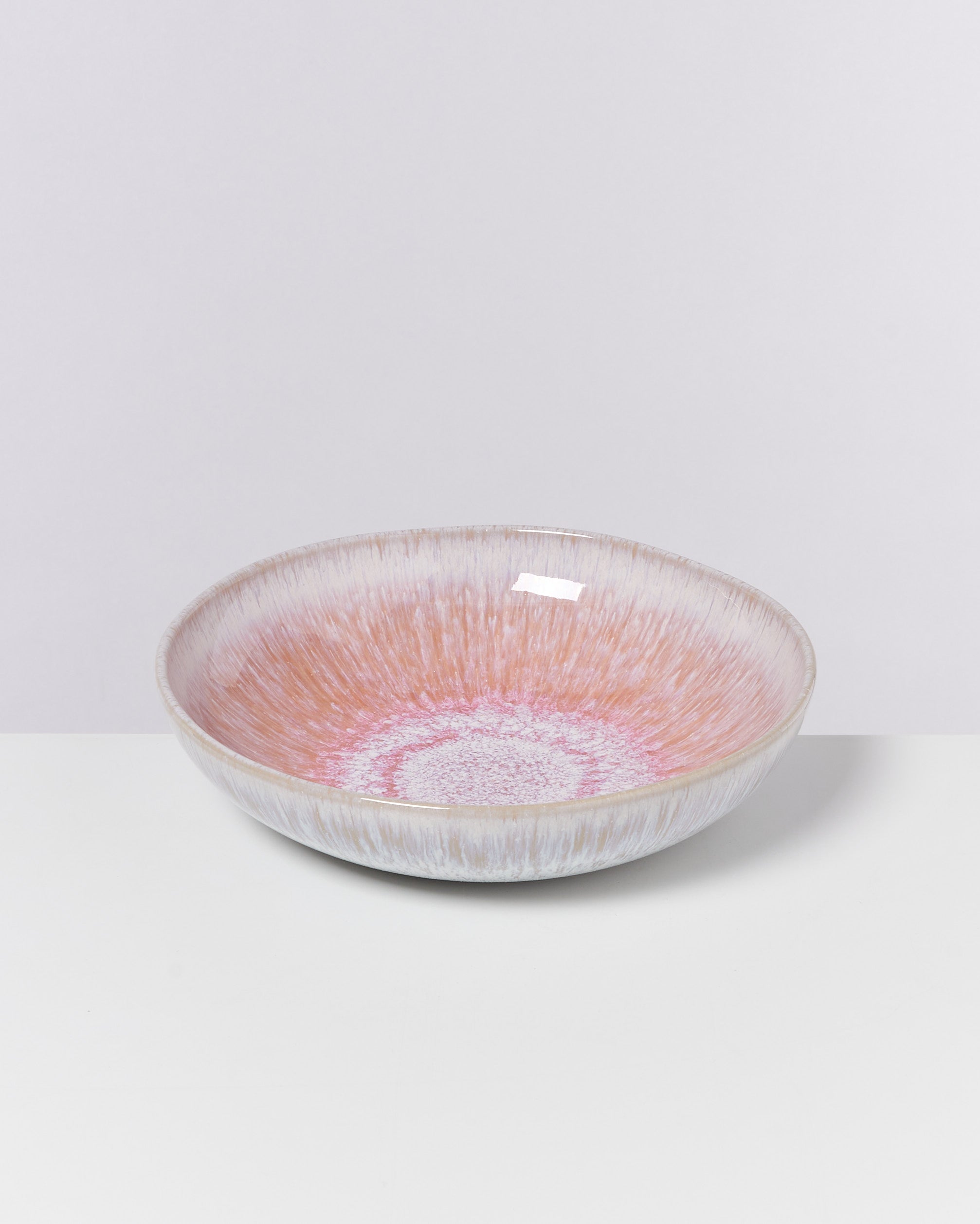 Flache, runde Schüssel mit zartem Farbverlauf in Rosa und Creme auf weißem Hintergrund.