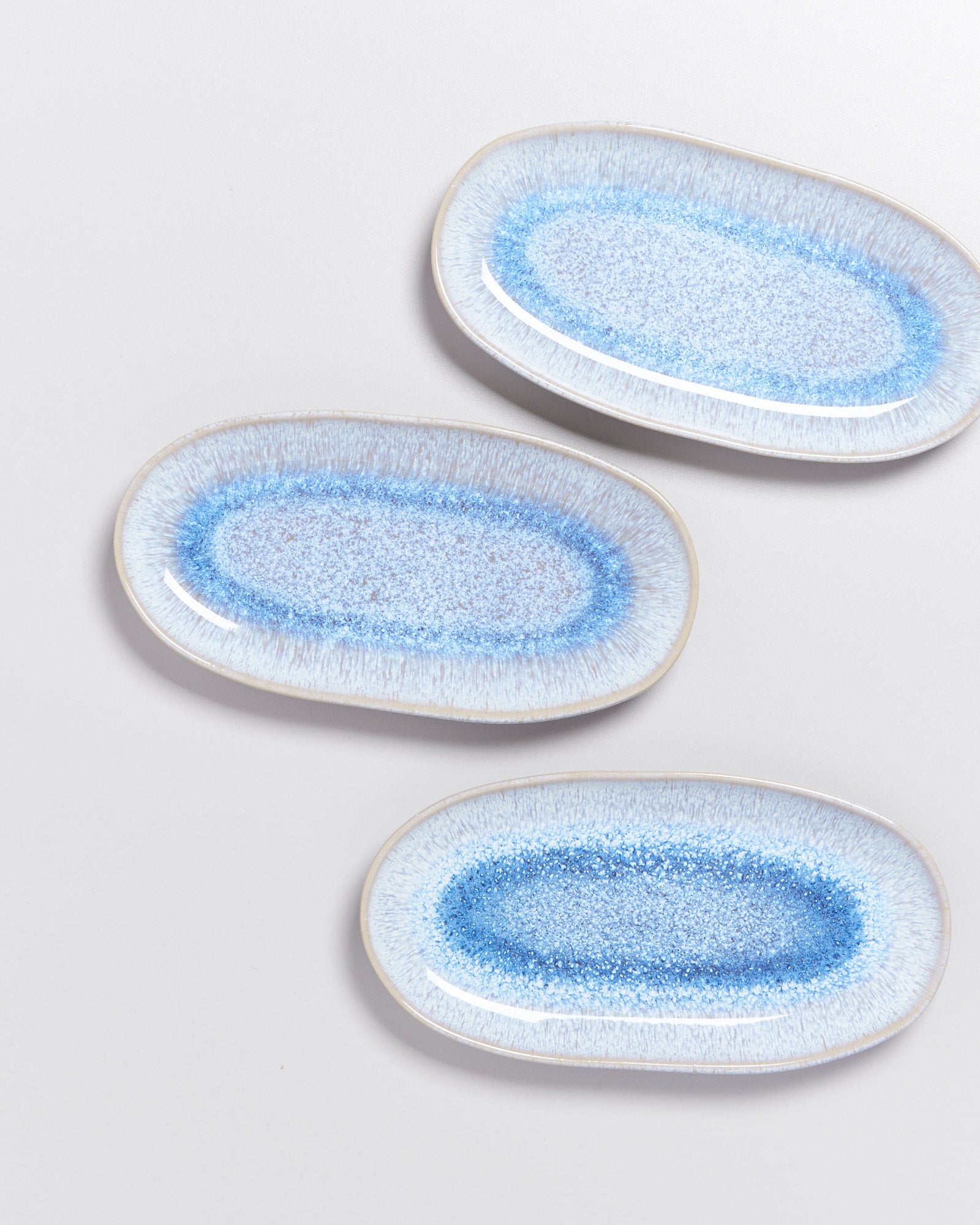 Drei ovale Teller mit blauem, gesprenkeltem Muster auf weißem Hintergrund.