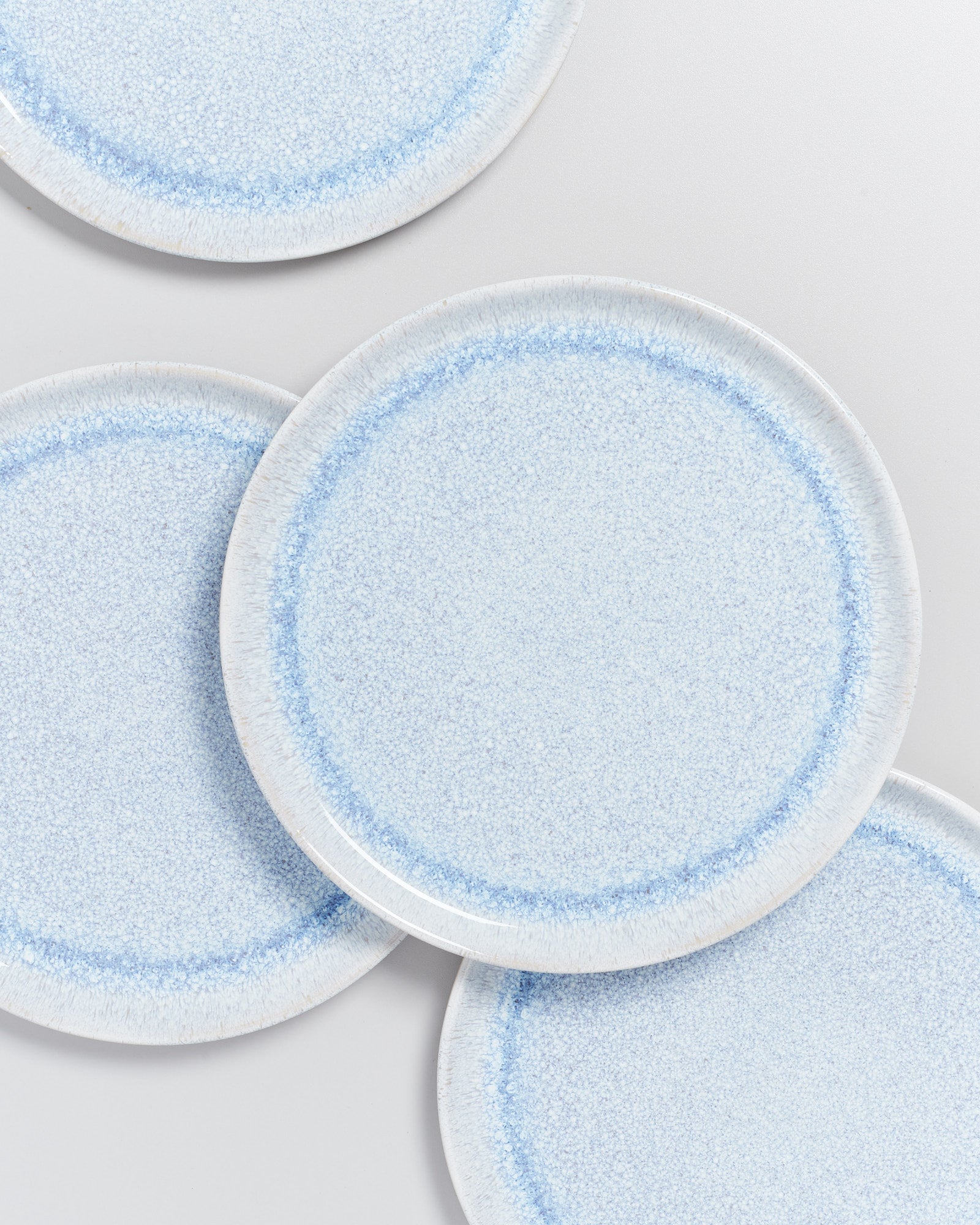 Vier blaue, gesprenkelte Teller auf einem weißen Hintergrund.