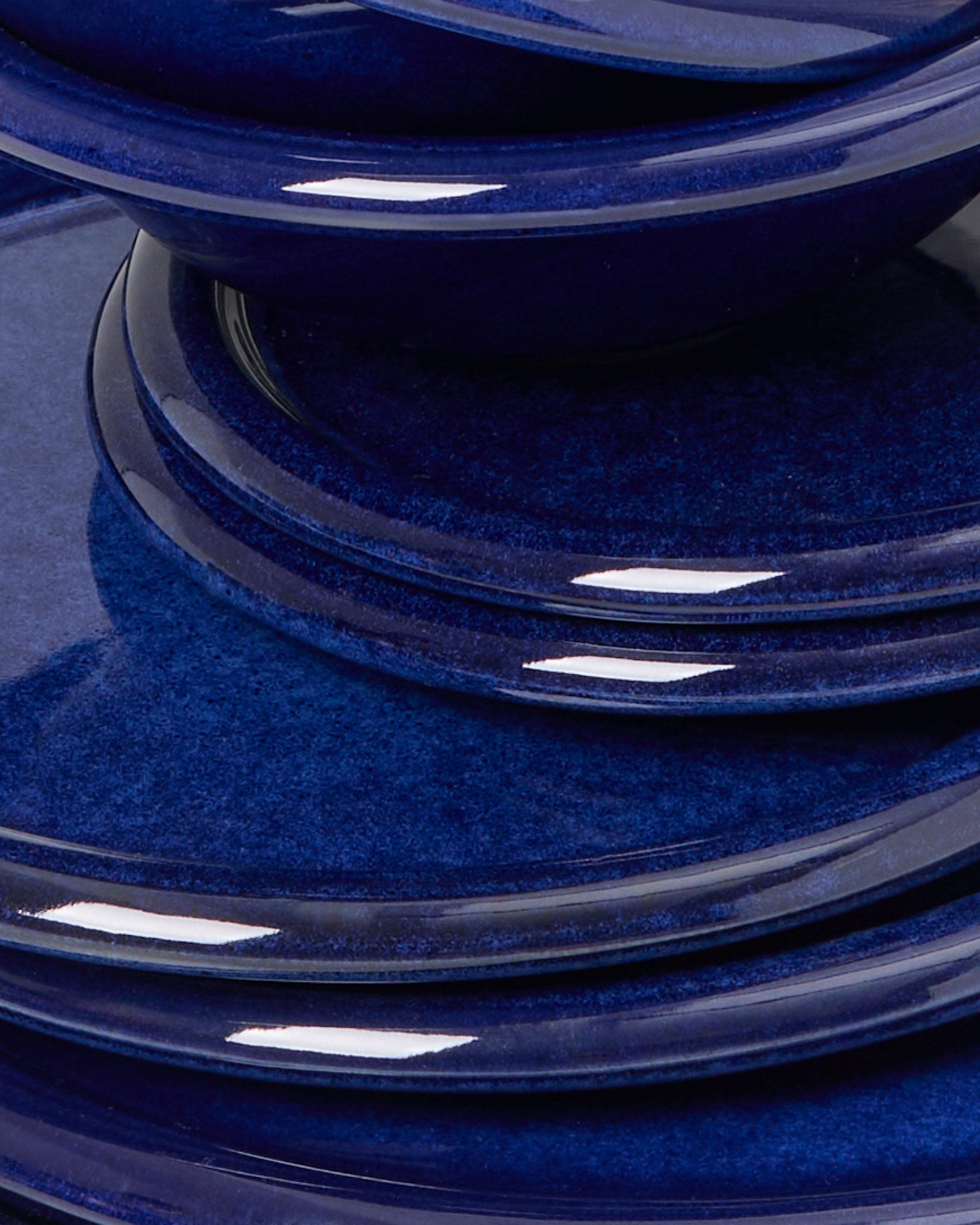 Ein Stapel von glänzenden, blauen Keramiktellern und -schüsseln.
