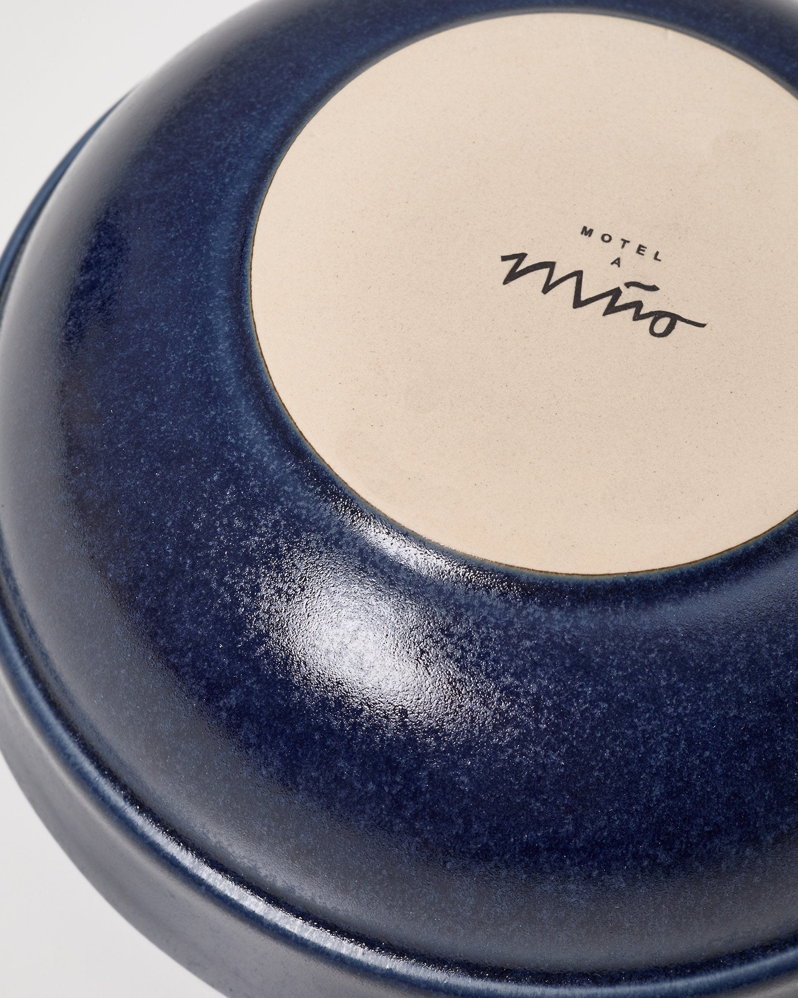Unterseite einer dunkelblauen Schale mit beigem Boden, auf dem "Motel a Miio" steht.