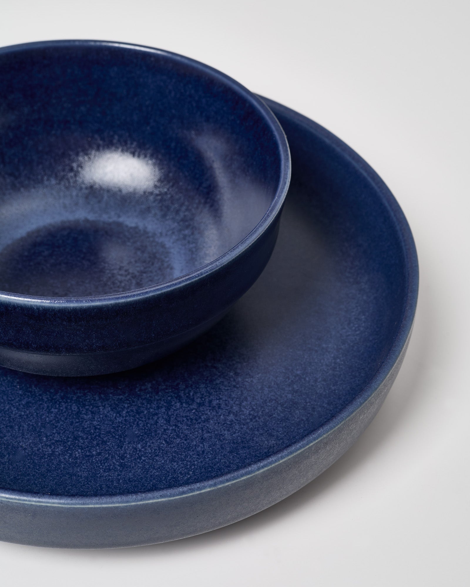 Dunkelblaue Schale auf passendem Teller vor neutralem Hintergrund.