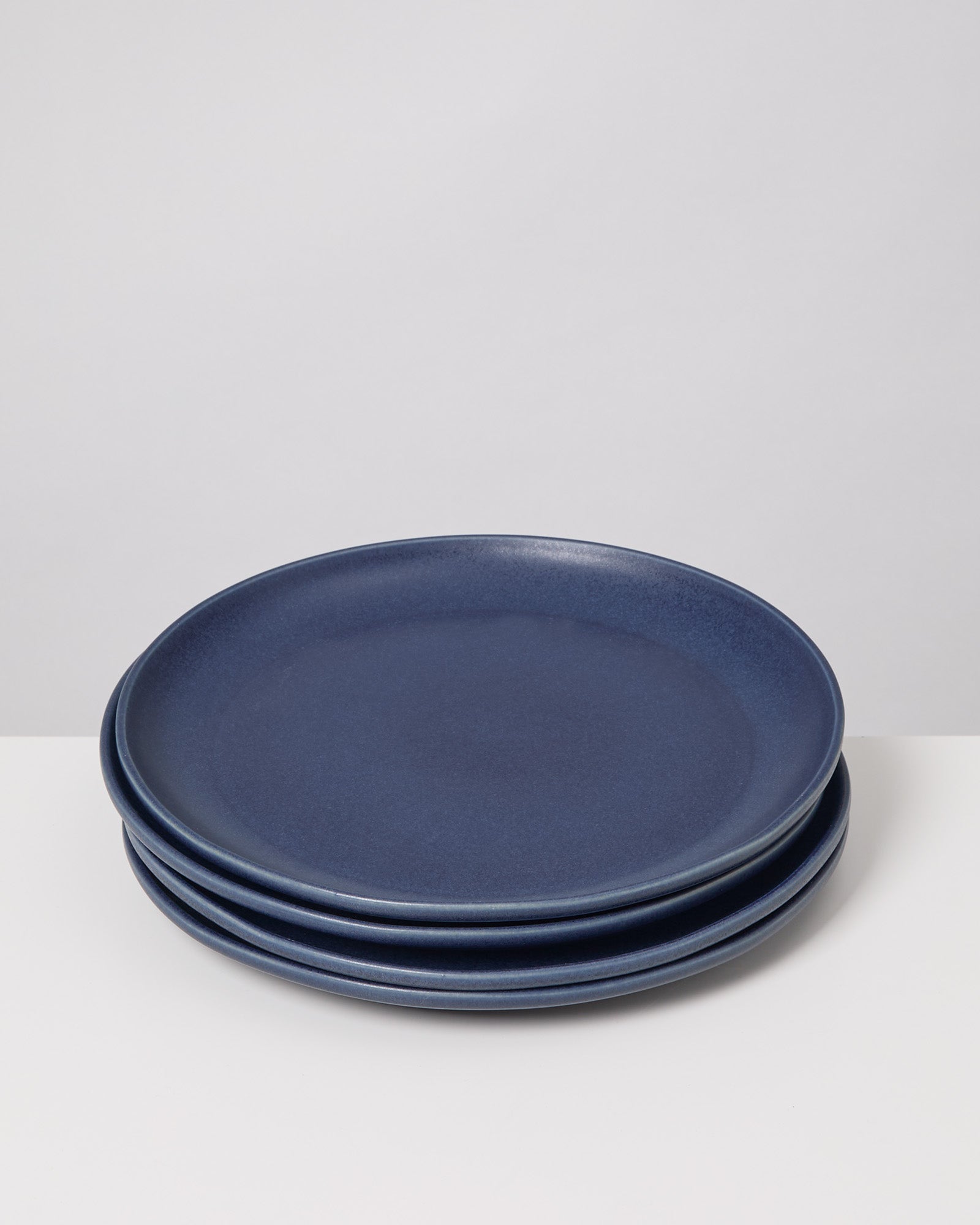 Drei gestapelte blaue Teller auf einem weißen Untergrund.