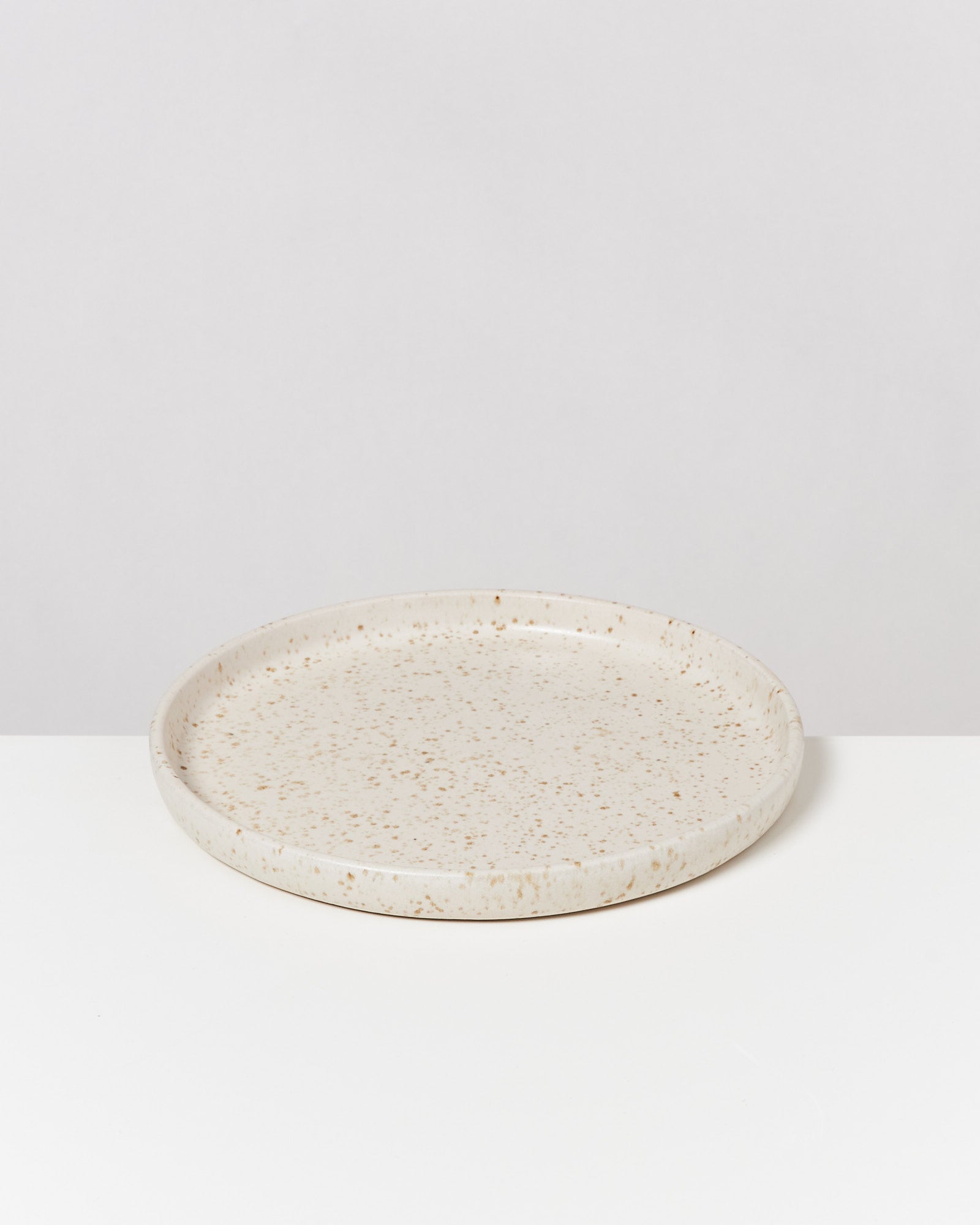 Keramikteller mit gesprenkeltem Muster auf weißem Hintergrund.