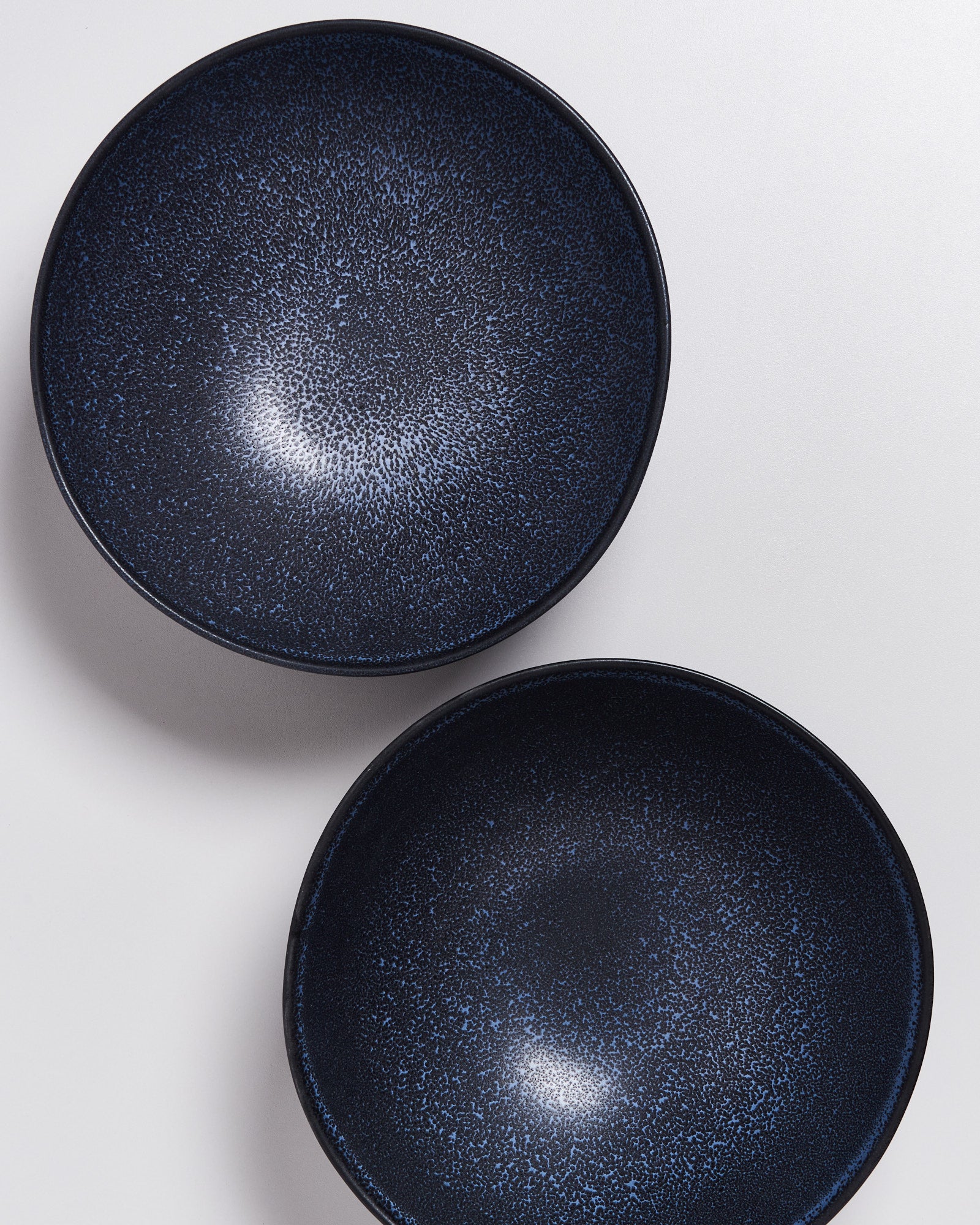 Zwei dunkelblaue Schalen mit gesprenkeltem Muster auf weißem Hintergrund.