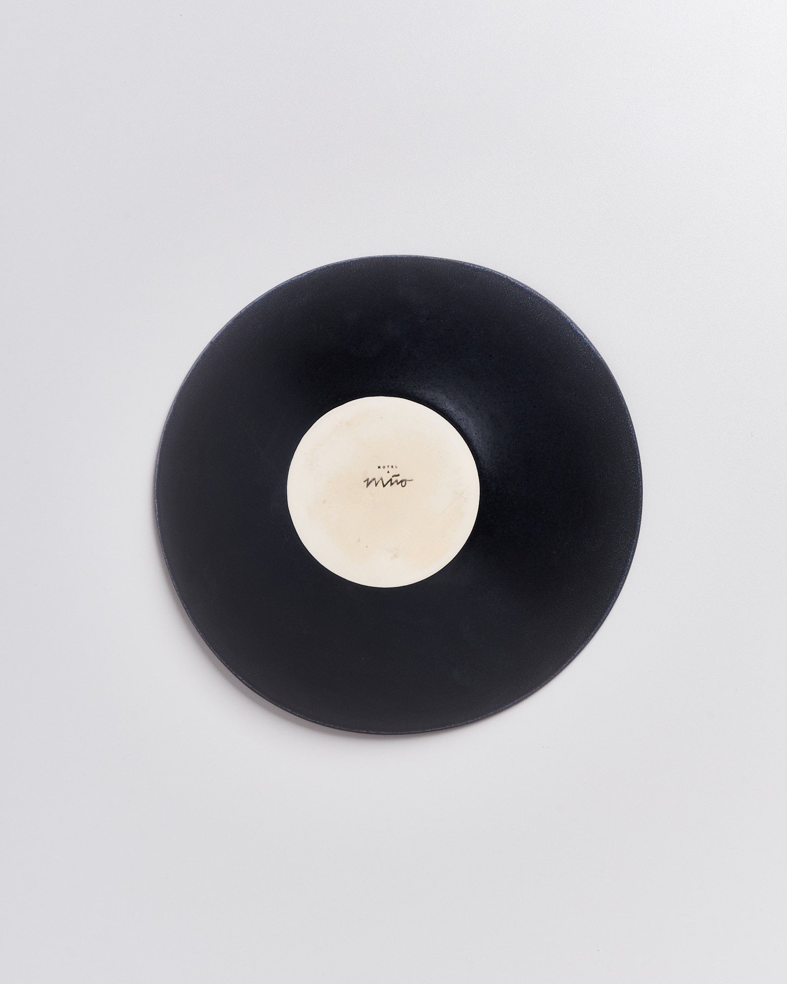 Schwarze Schallplatte mit weißem Etikett in der Mitte auf hellem Hintergrund.