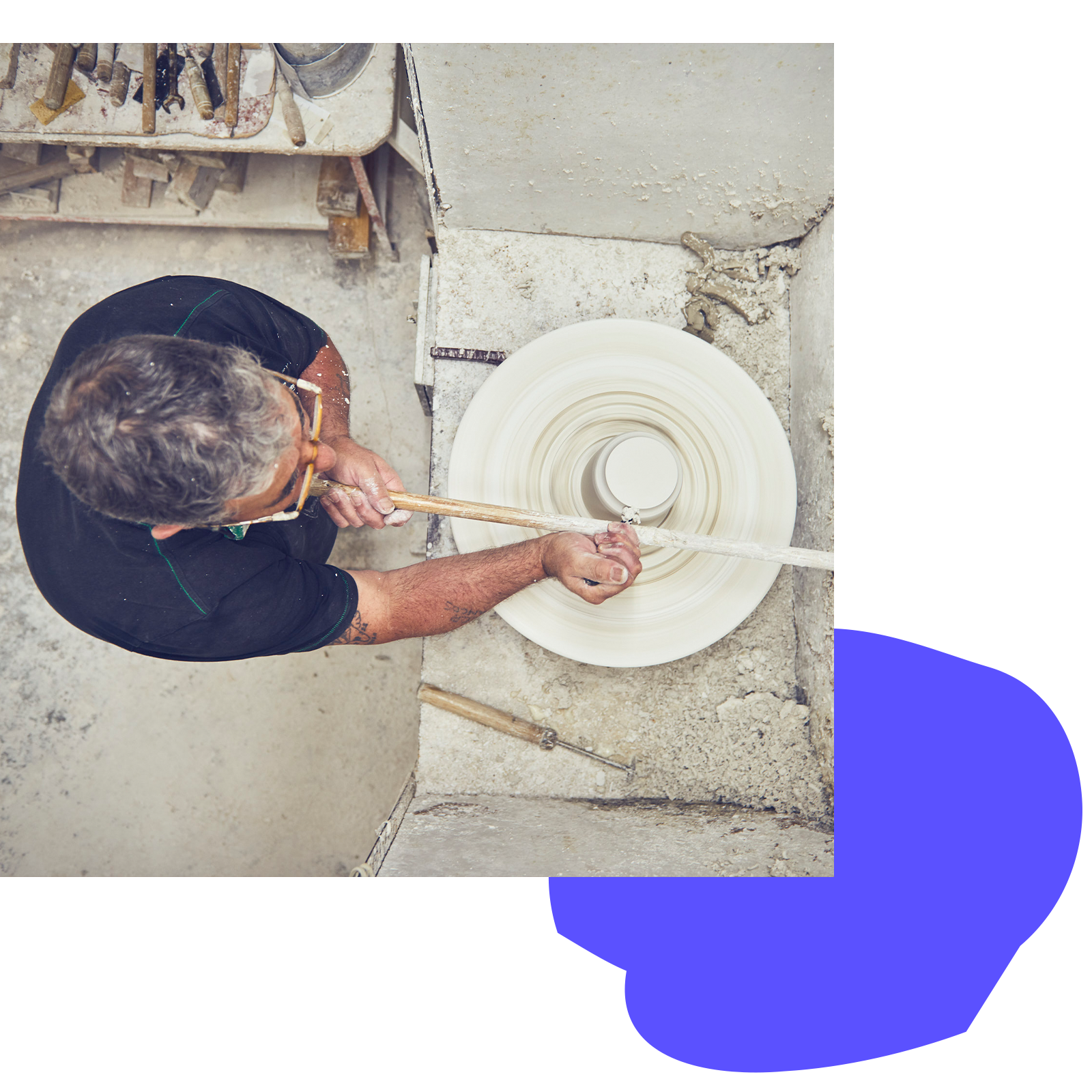 Mann betrachtet aus der Vogelperspektive einen rotierenden Töpferteller in einer Werkstatt.