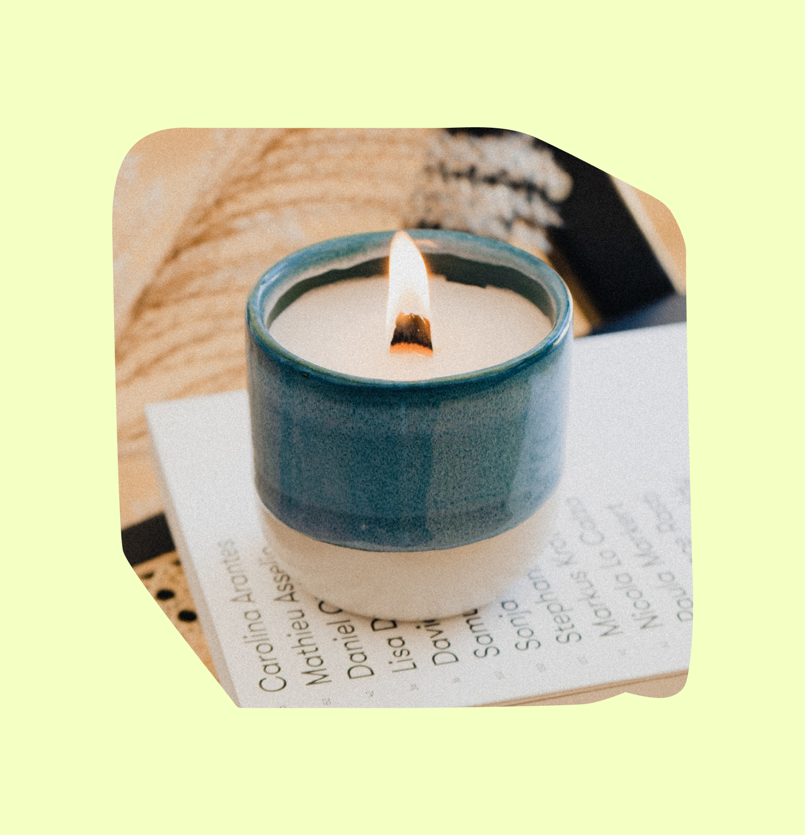 Brennende Kerze in blauer Keramikschale auf Büchern vor hellem Hintergrund.