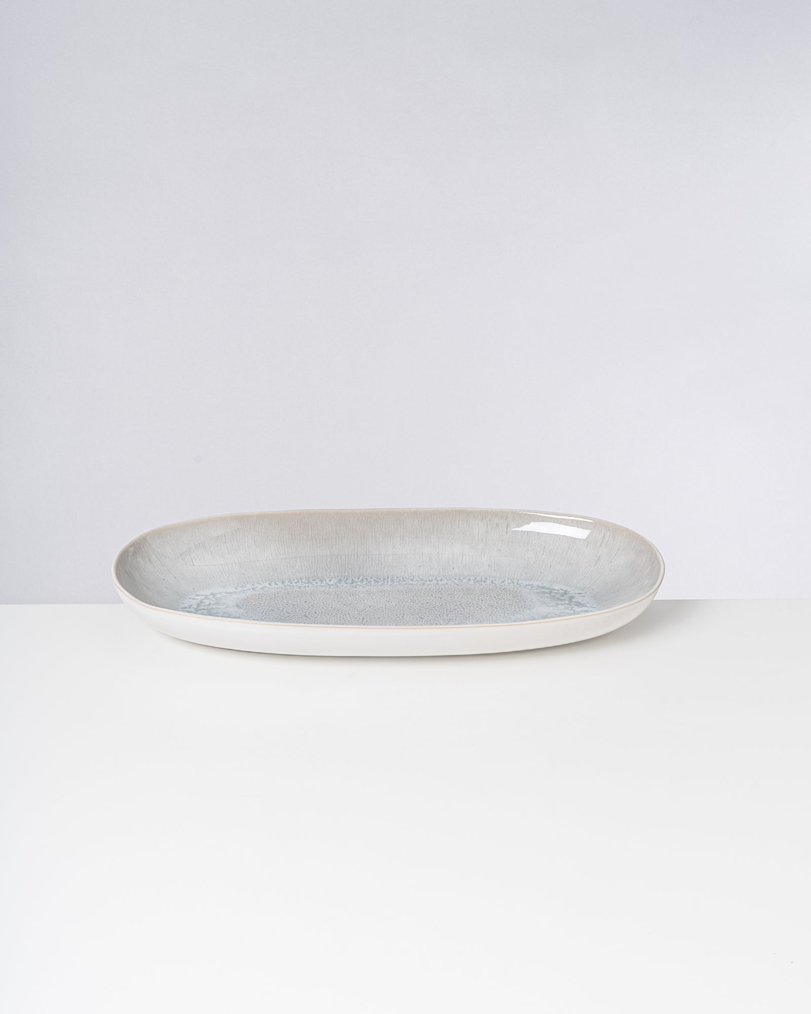 Keramikteller mit cremefarbenem Rand und grauer Innenseite auf weißem Hintergrund.