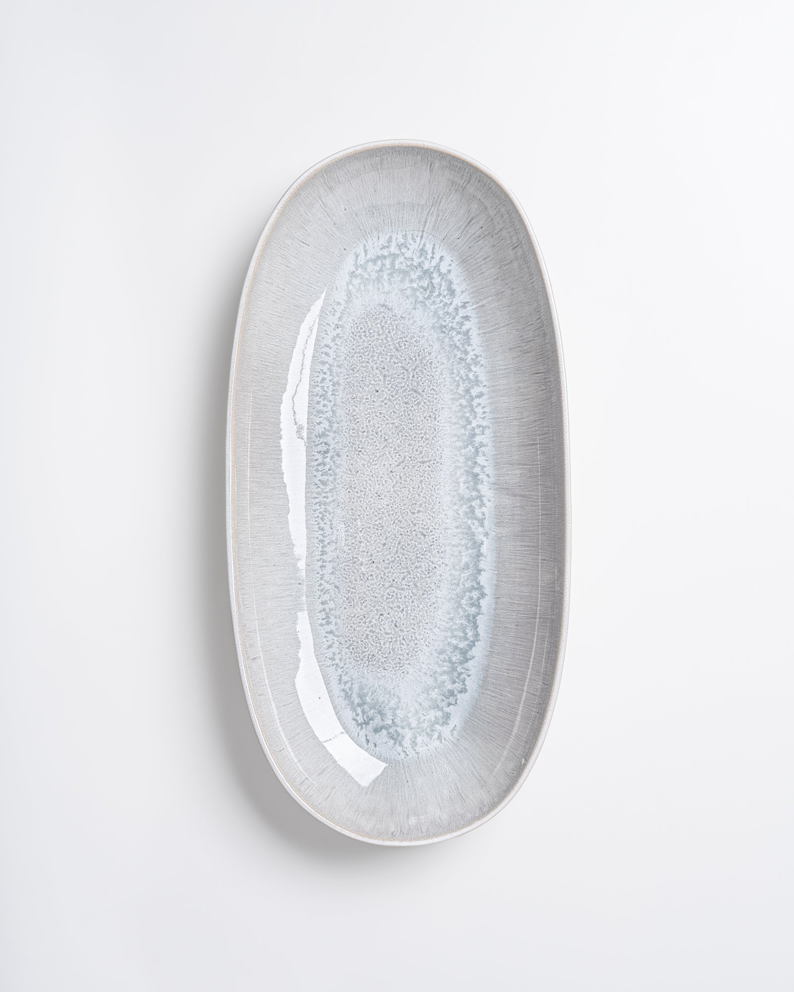 Graue, ovale Keramikplatte mit strukturiertem, gesprenkeltem Muster auf weißem Hintergrund.
